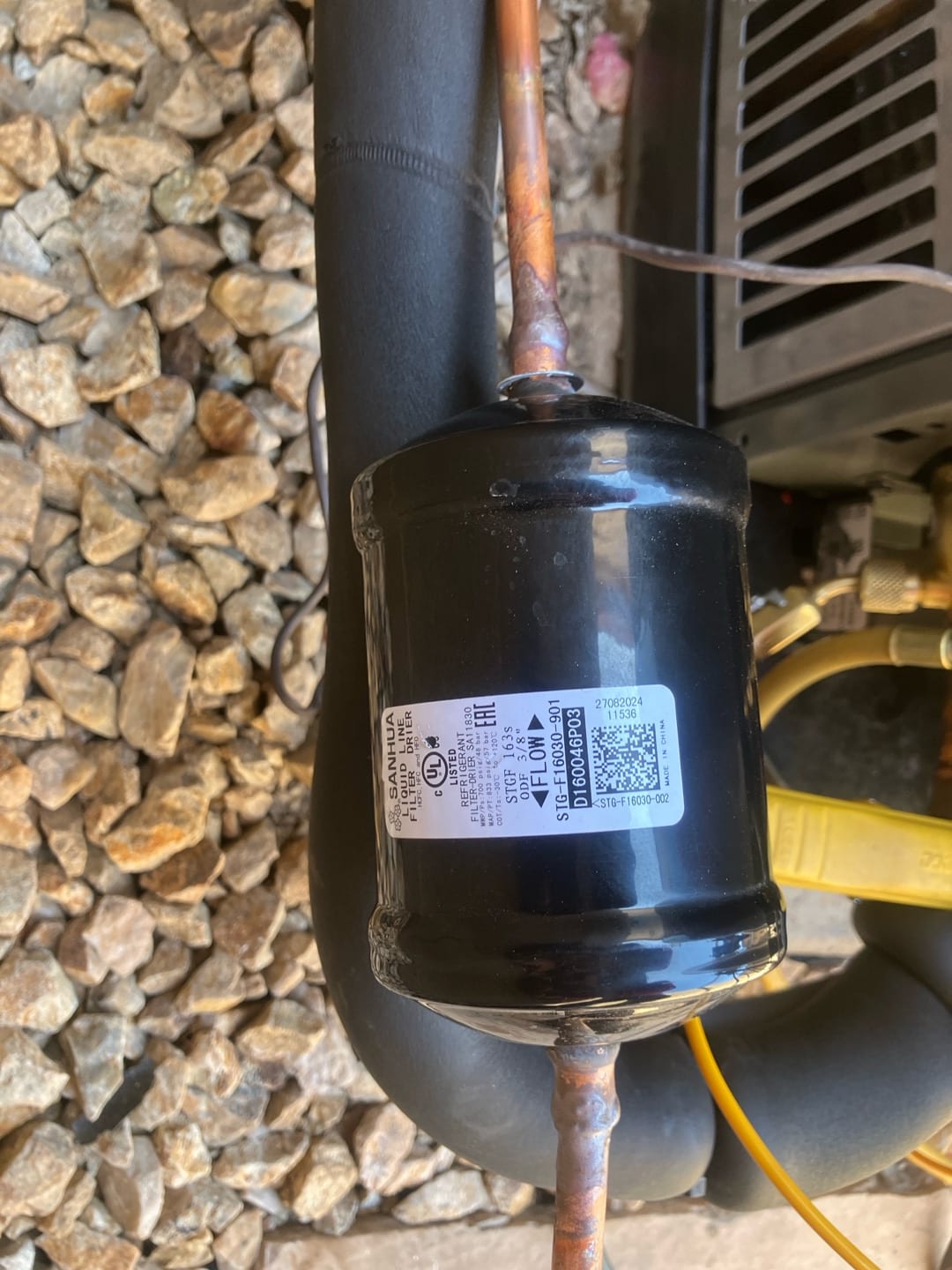 Installed inline filter-drier brazed into the copper refrigerant line beside the outdoor condenser unit with insulated suction line.