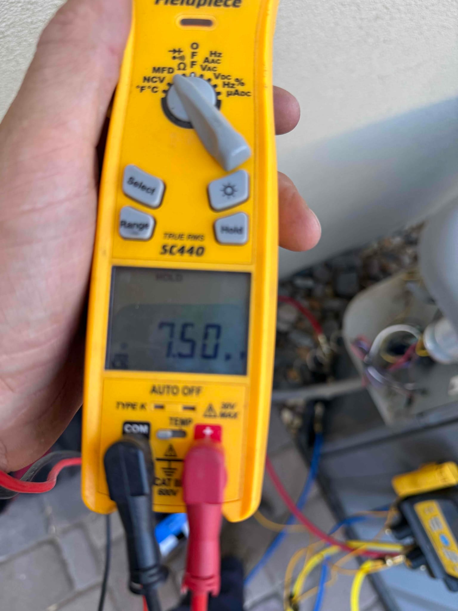 Multimeter clamp reads 7.50 A on a conductor at the outdoor condenser during operation.