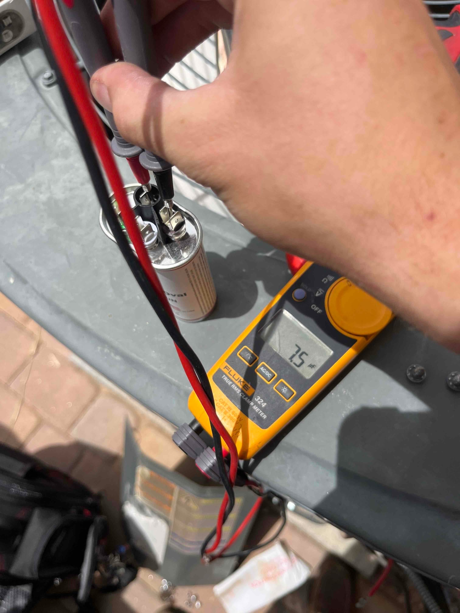 Multimeter measures 7.5 μF across the capacitor terminals while probes contact the component during testing.