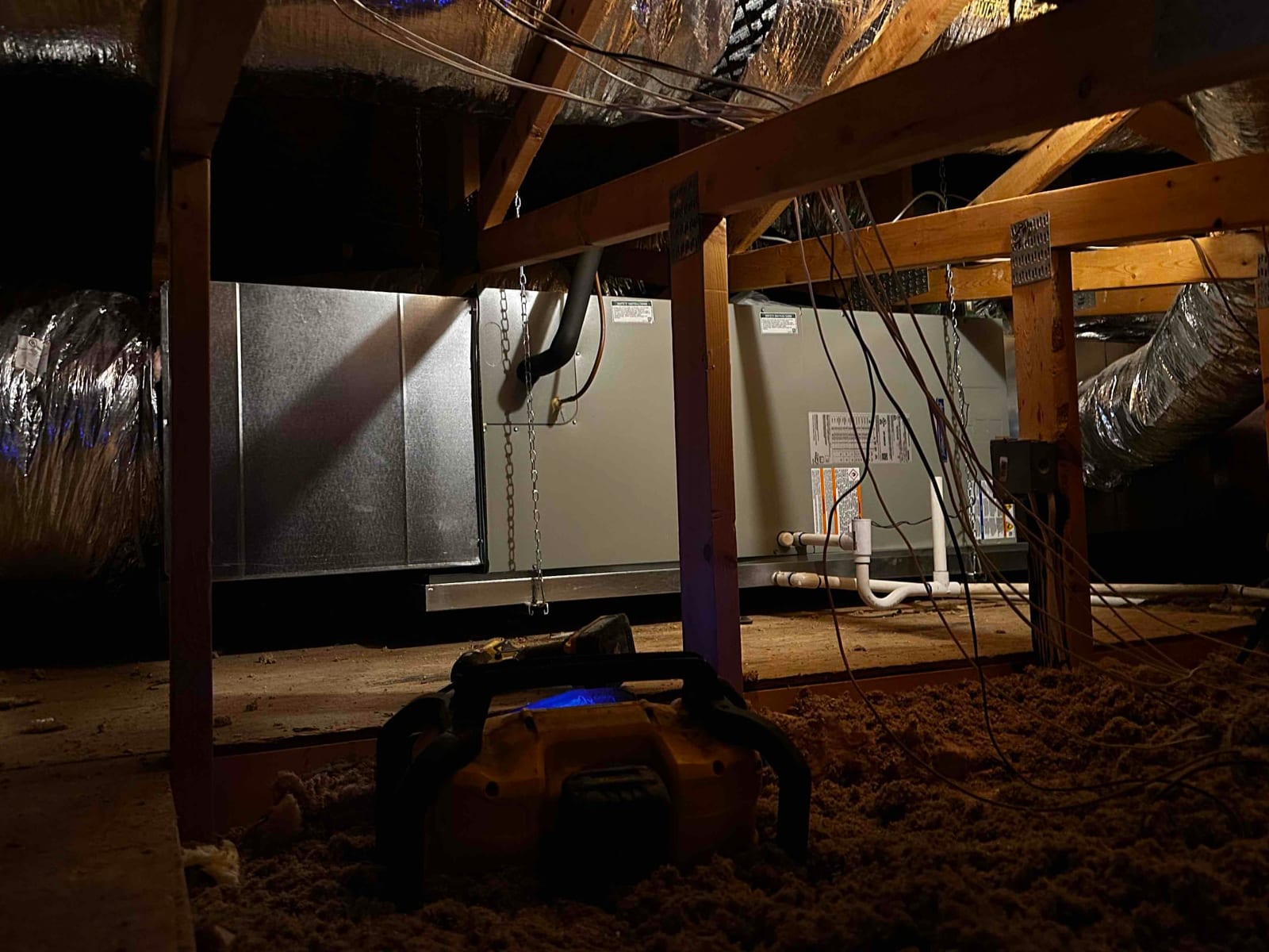 New attic air handler and duct connections installed on a suspended platform with insulated flex ducts and PVC condensate drain piping.