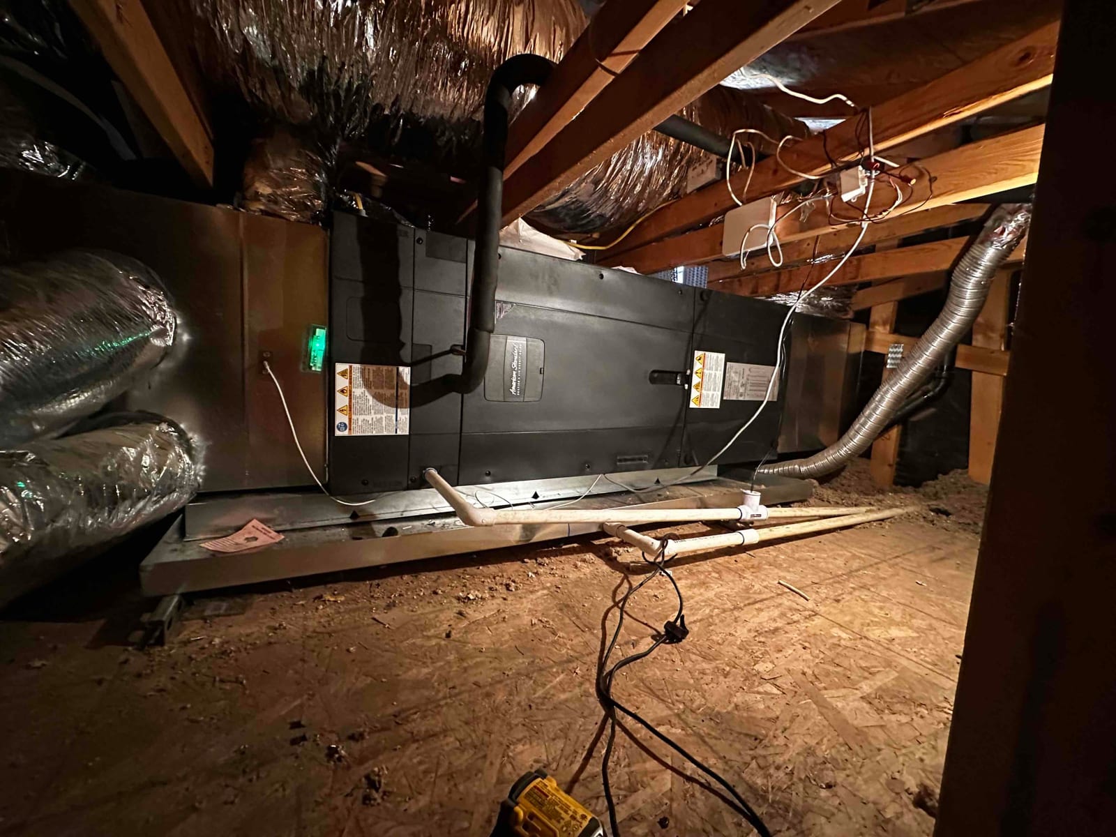 New attic air handler installed on a secondary drain pan with insulated duct connections and condensate drain piping routed to a float switch.
