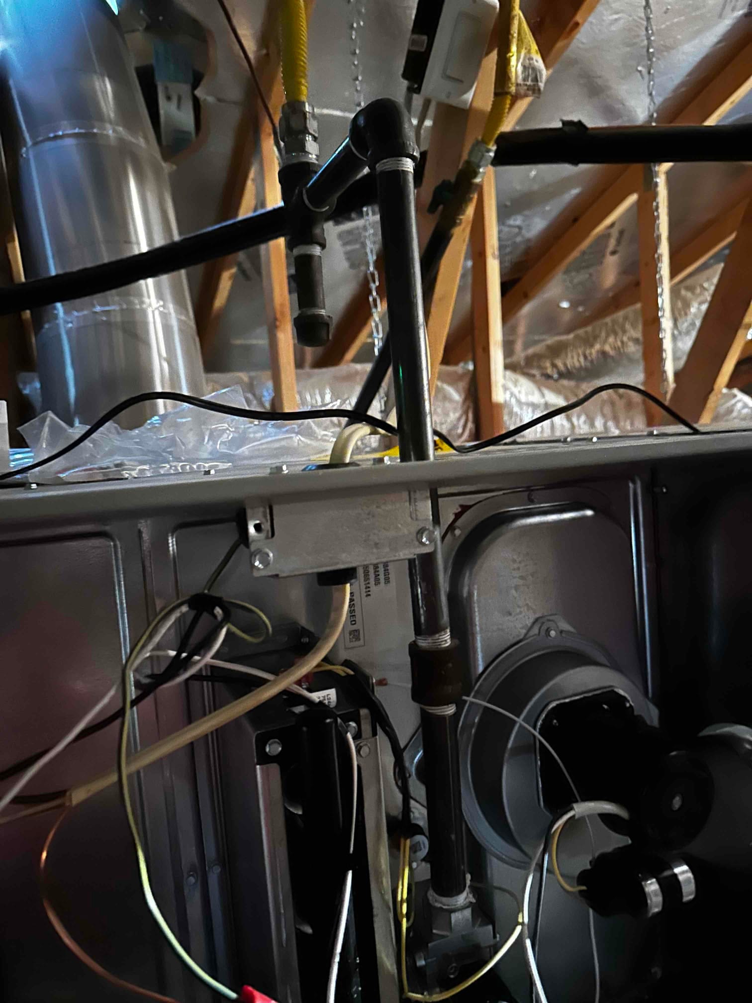 New gas furnace installation showing black iron gas piping with drip leg, flex connectors, and internal wiring at the blower compartment.