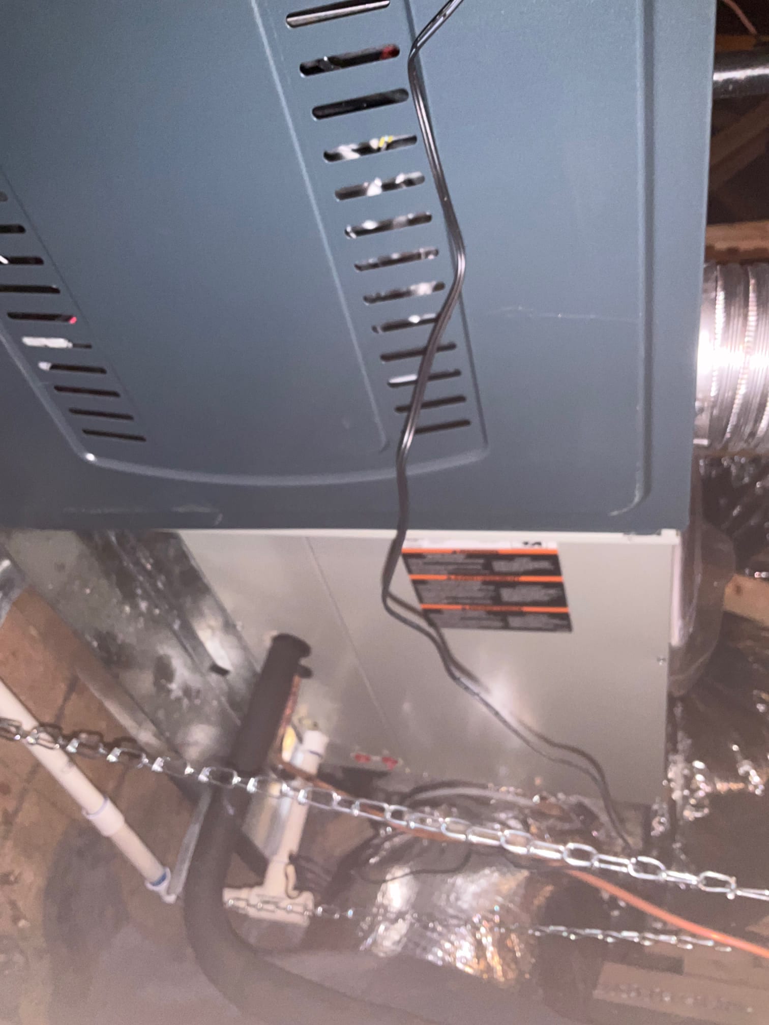 New indoor unit suspended with chains, connected to insulated refrigerant lines and condensate drain piping within the attic space.
