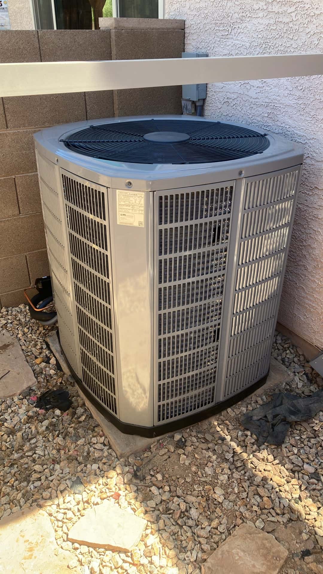 New outdoor condenser set on a level pad beside the home, with disconnect mounted and insulated refrigerant lines routed to the unit.