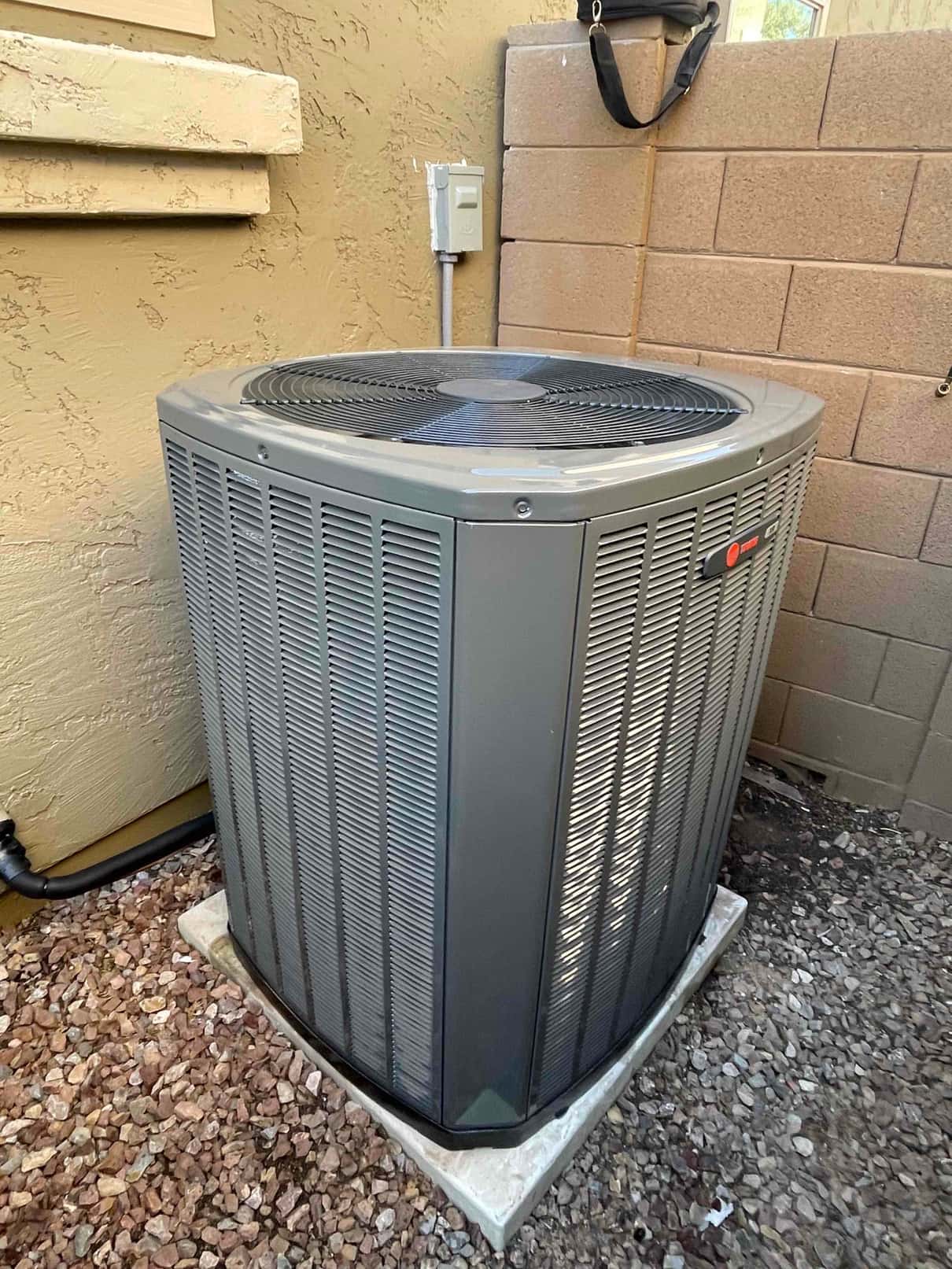 New outdoor condenser set on a level pad with insulated line set and nearby electrical disconnect in place.
