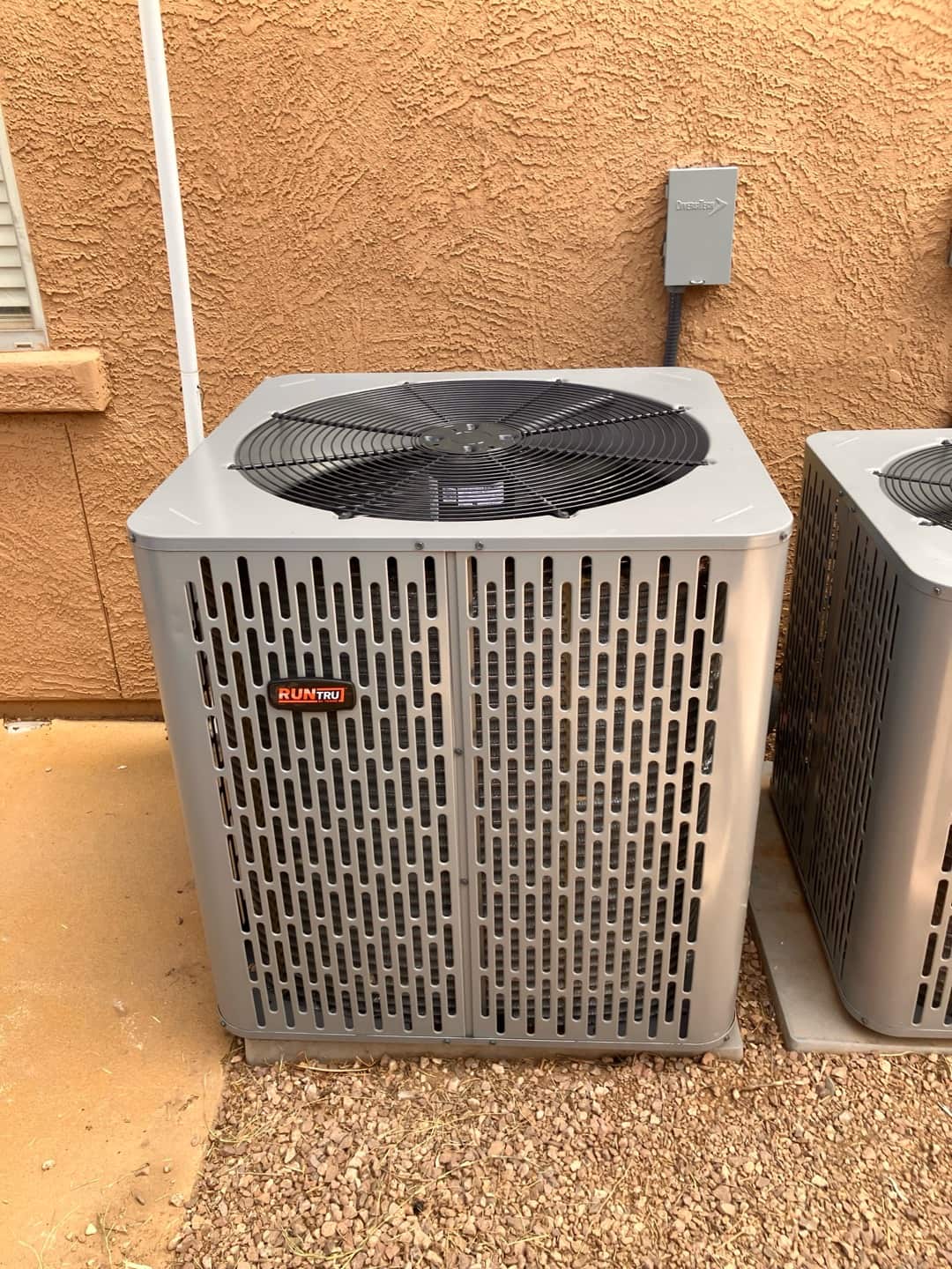 New outdoor condenser set on a level pad with nearby electrical disconnect mounted on the wall.