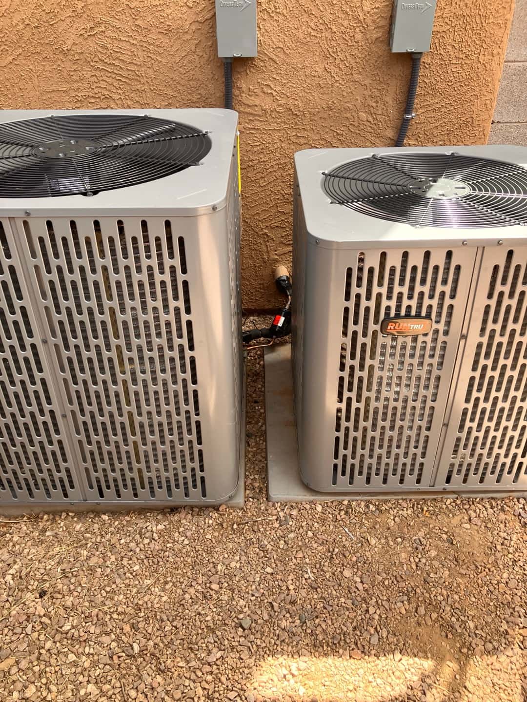 Two new outdoor condenser units set on level pads with insulated refrigerant lines and dedicated electrical disconnects mounted on the wall.