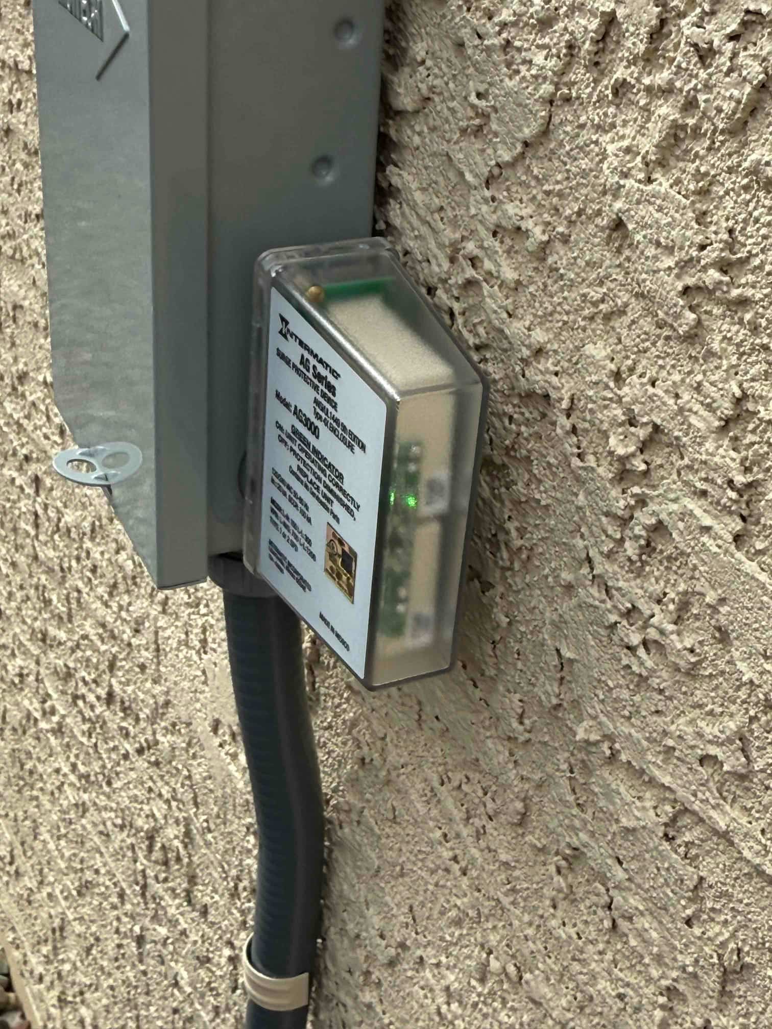 Outdoor disconnect with a protective device mounted beside flexible conduit, showing indicator lights illuminated during installation.
