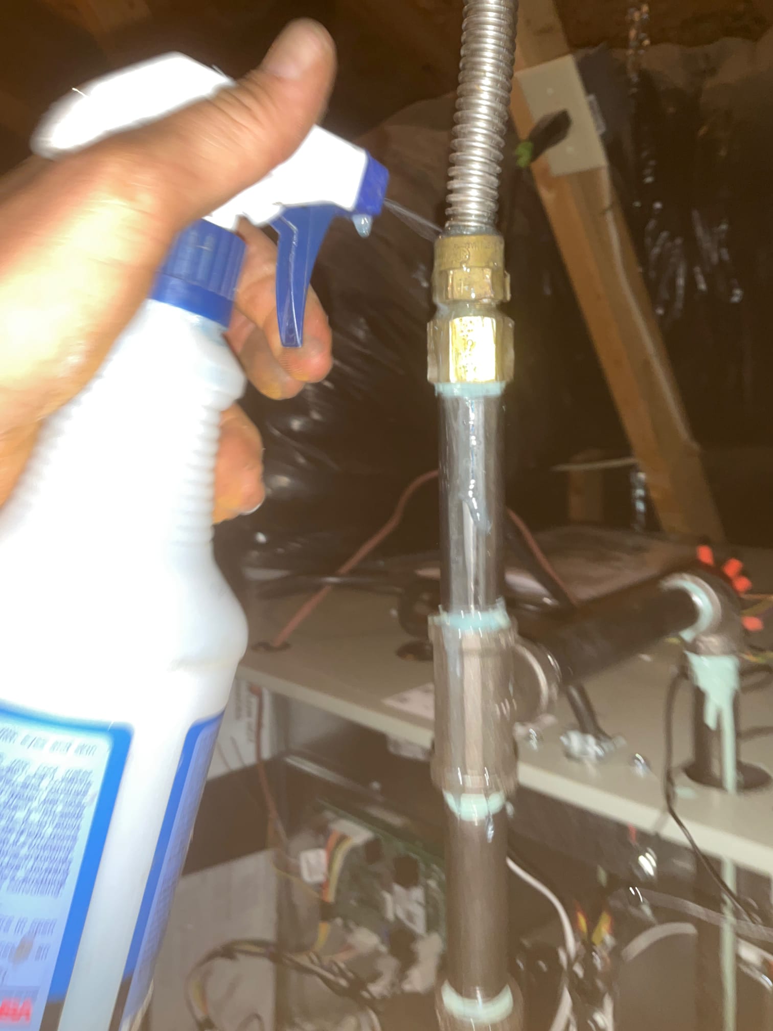 Technician sprays leak-detection solution on a gas pipe fitting near the furnace to check for bubbles.