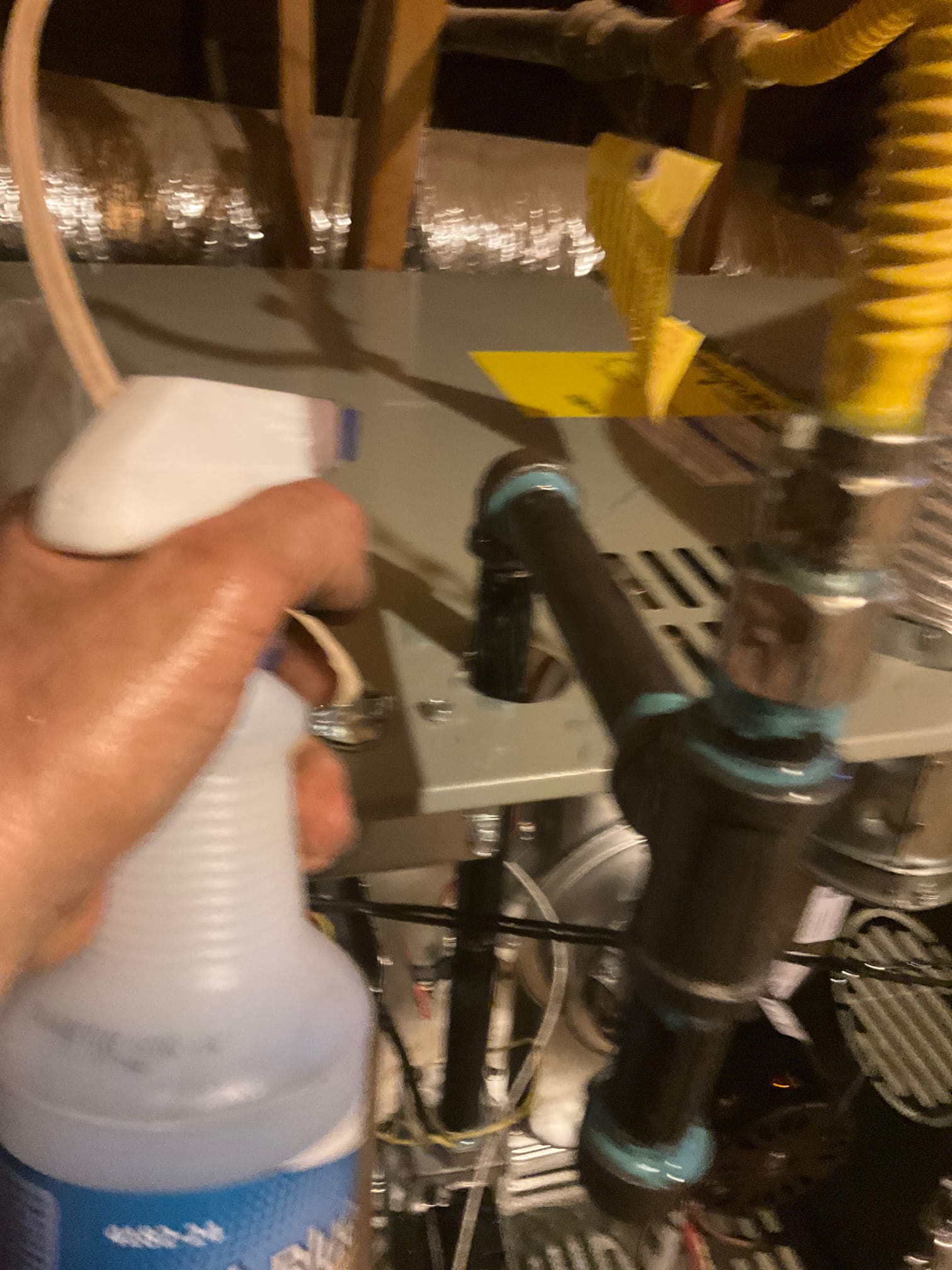 Technician sprays leak detector on new gas piping connections at the attic air handler to check for bubbles.