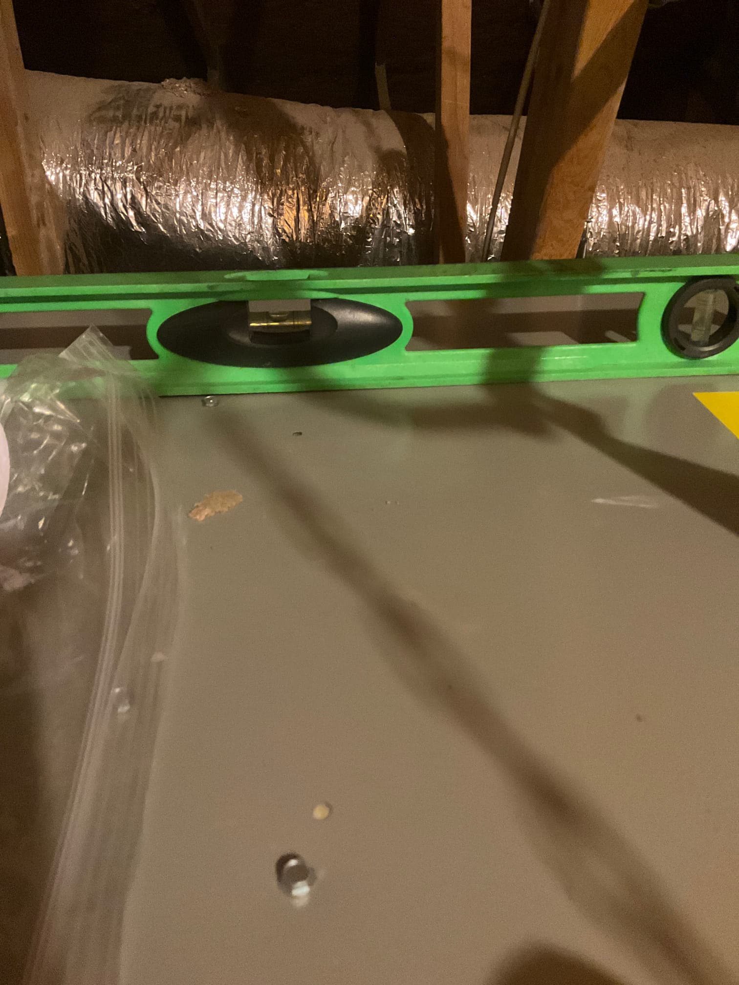 Torpedo level on top of an attic air handler, confirming the unit is set level during installation.