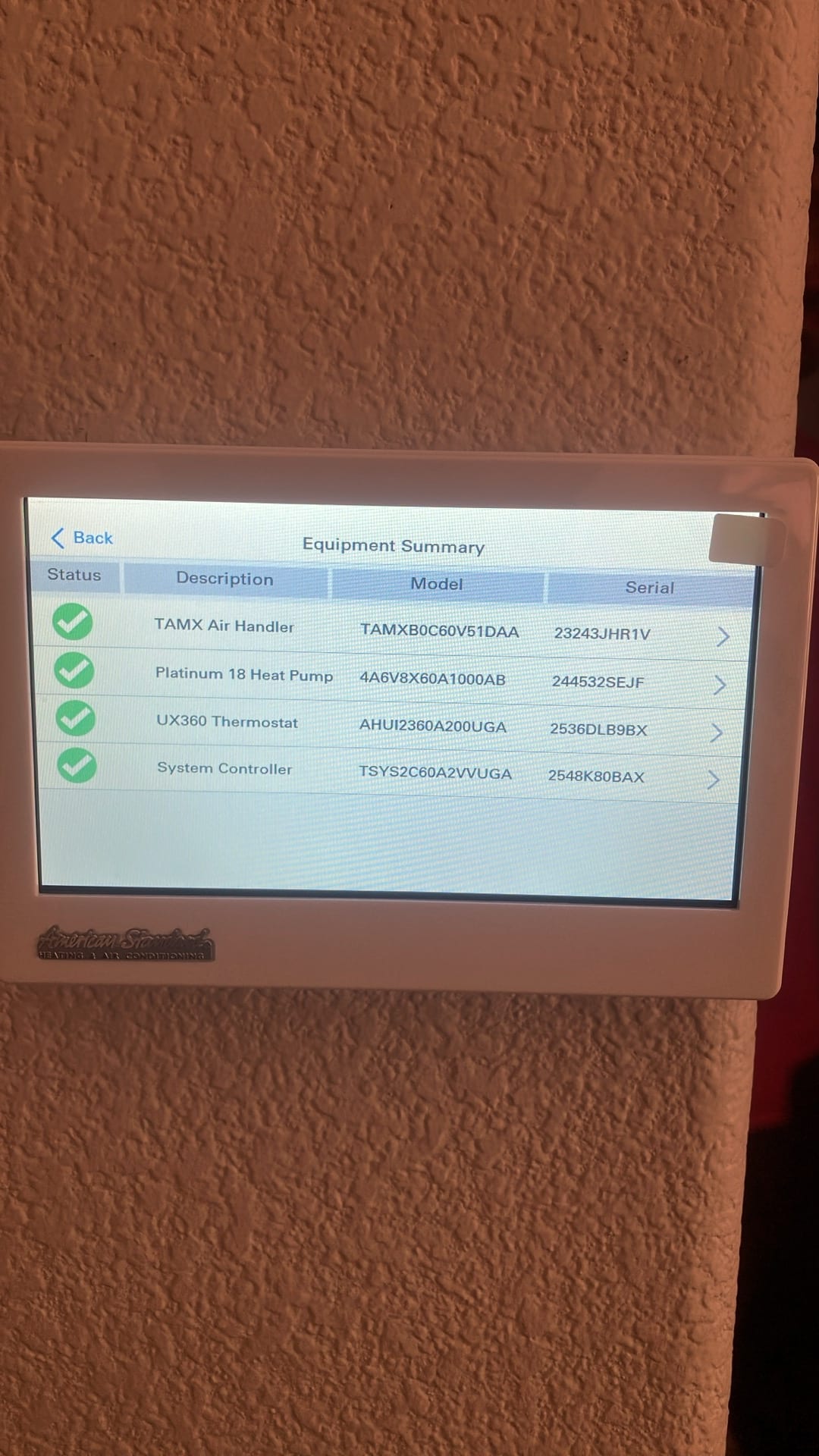 Touchscreen thermostat displays an equipment summary with connected air handler, heat pump, thermostat, and system controller all checked in green.