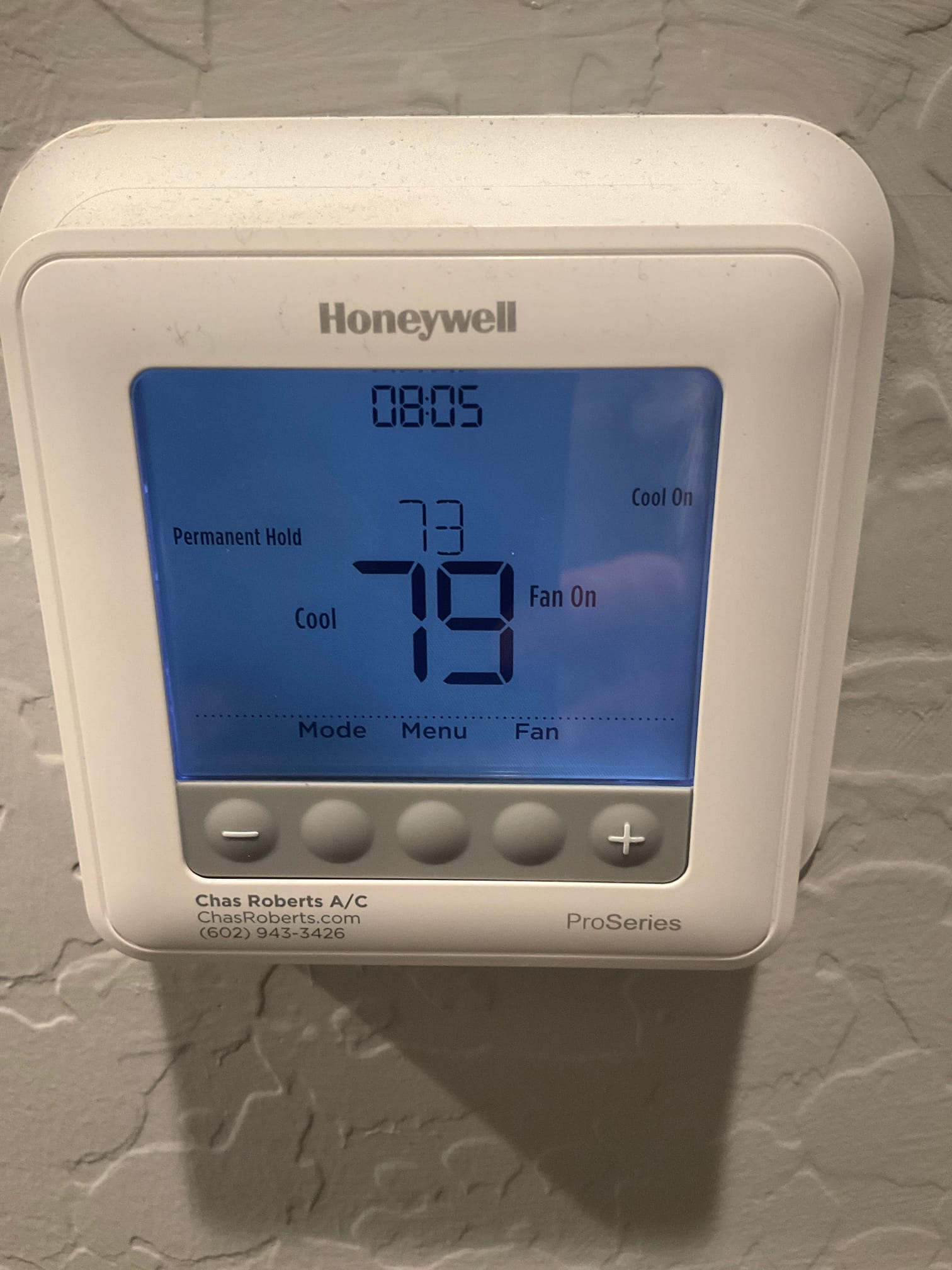 Wall-mounted thermostat display shows 79°F indoor temperature, set to 73°F, cooling and fan on, permanent hold.