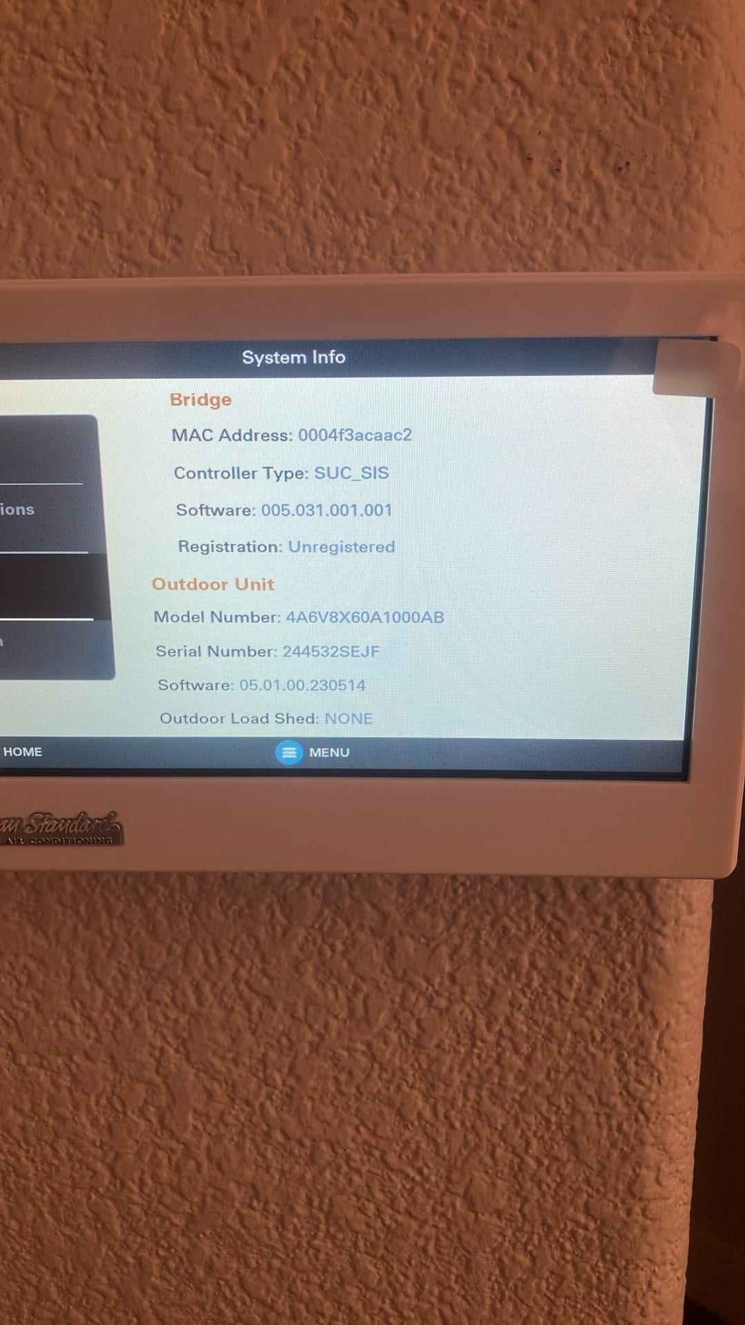 Wall-mounted thermostat displays system information screen with network bridge details and outdoor unit software status during setup.