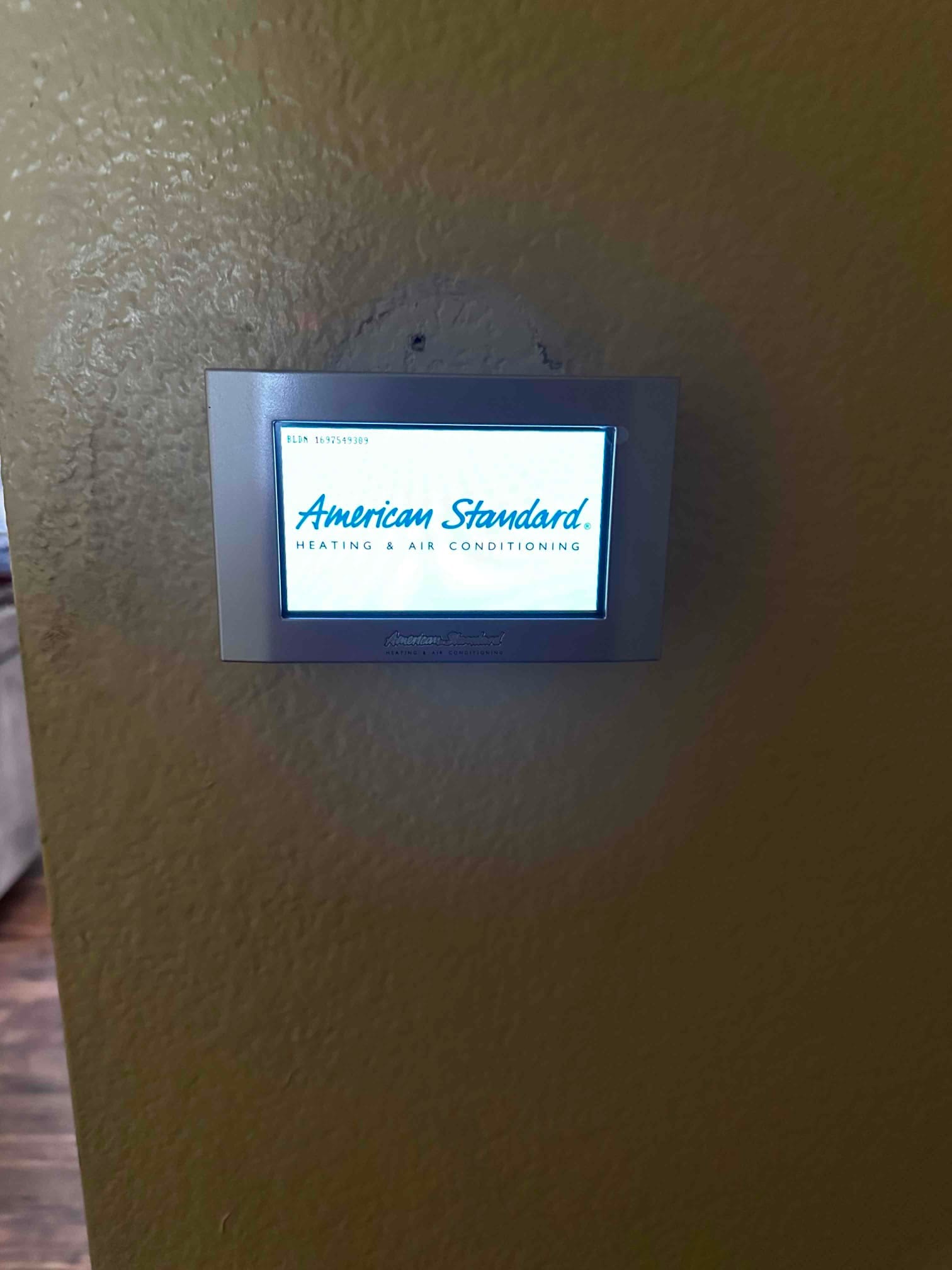 Wall-mounted thermostat installed and powered on, displaying the startup screen for the new HVAC control.