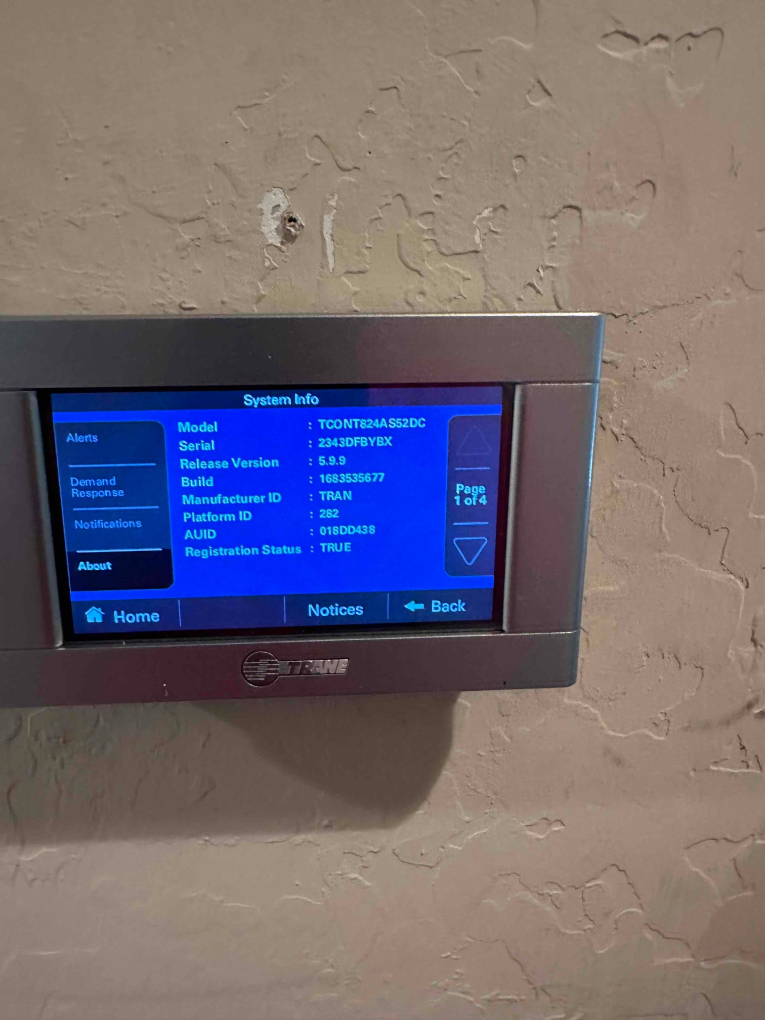 Wall-mounted touchscreen thermostat displaying system information menu after installation and setup.
