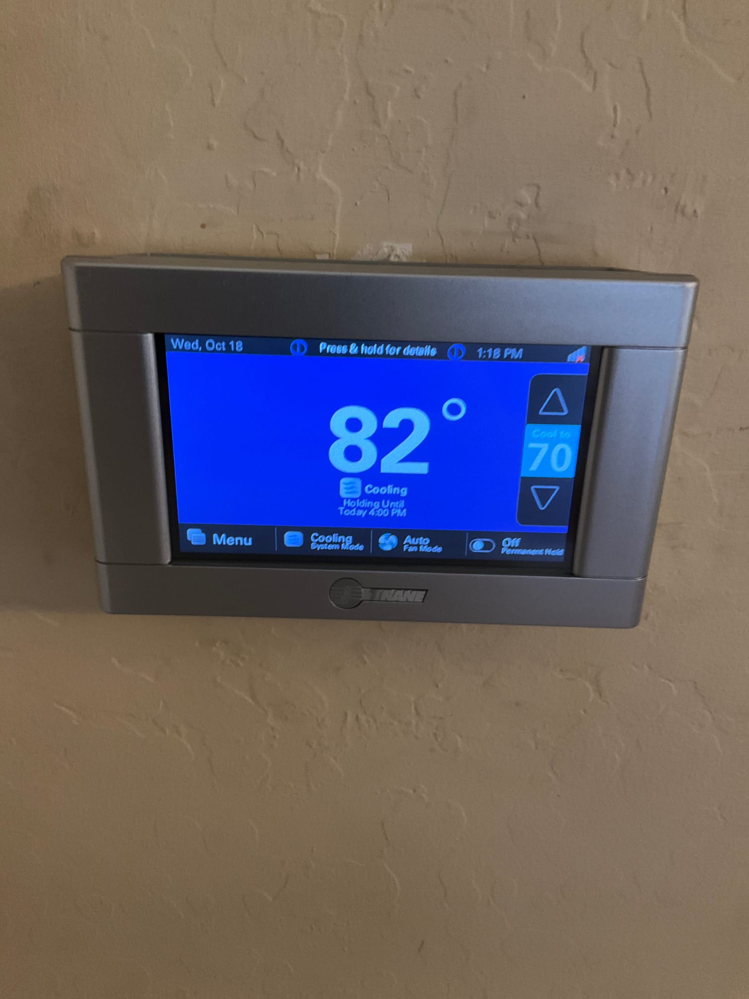 Wall-mounted touchscreen thermostat displays 82 degrees with cooling active and a setpoint of 70 degrees.