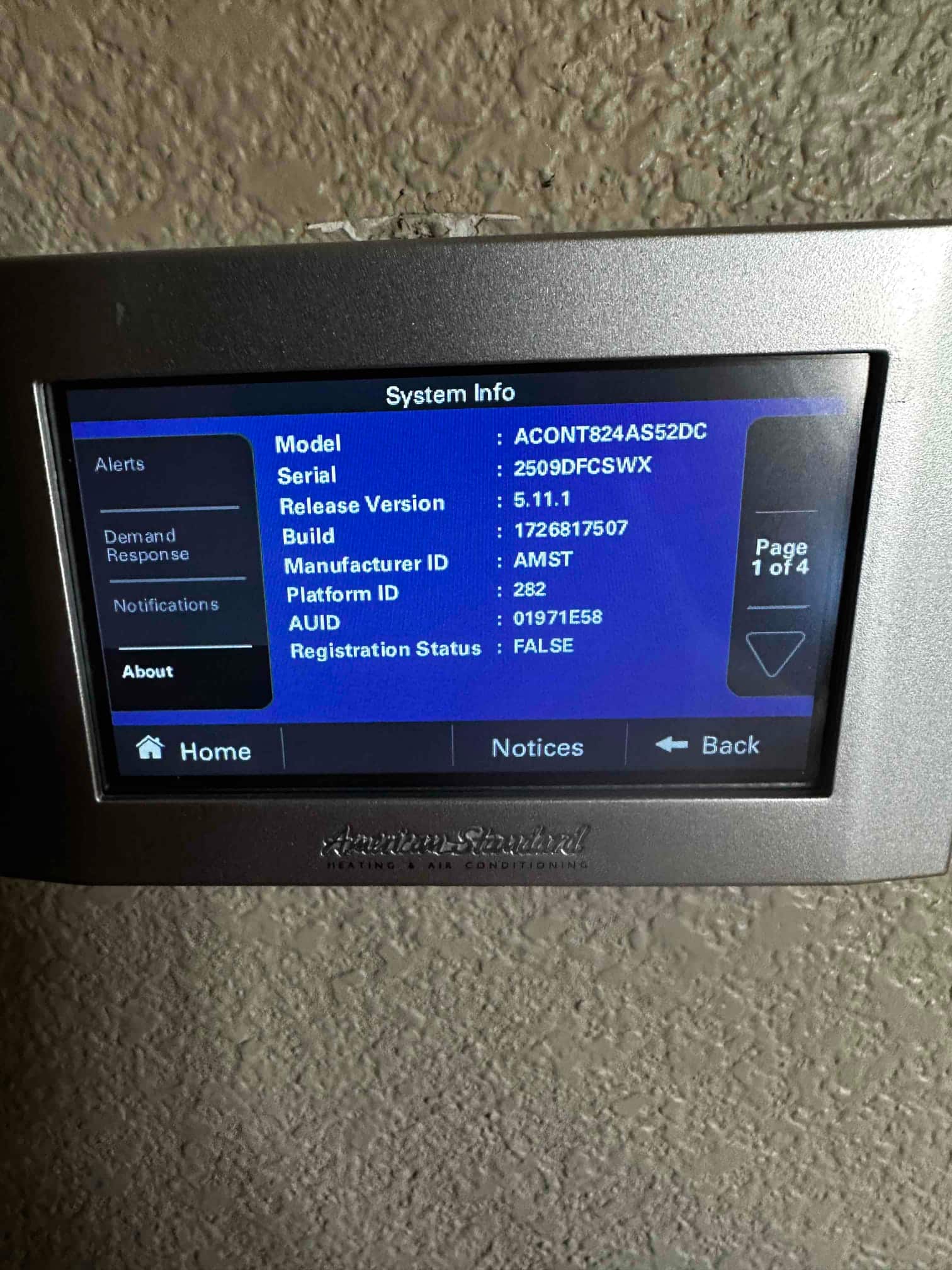 Wall-mounted touchscreen thermostat displays system information menu after installation at the indoor control location.
