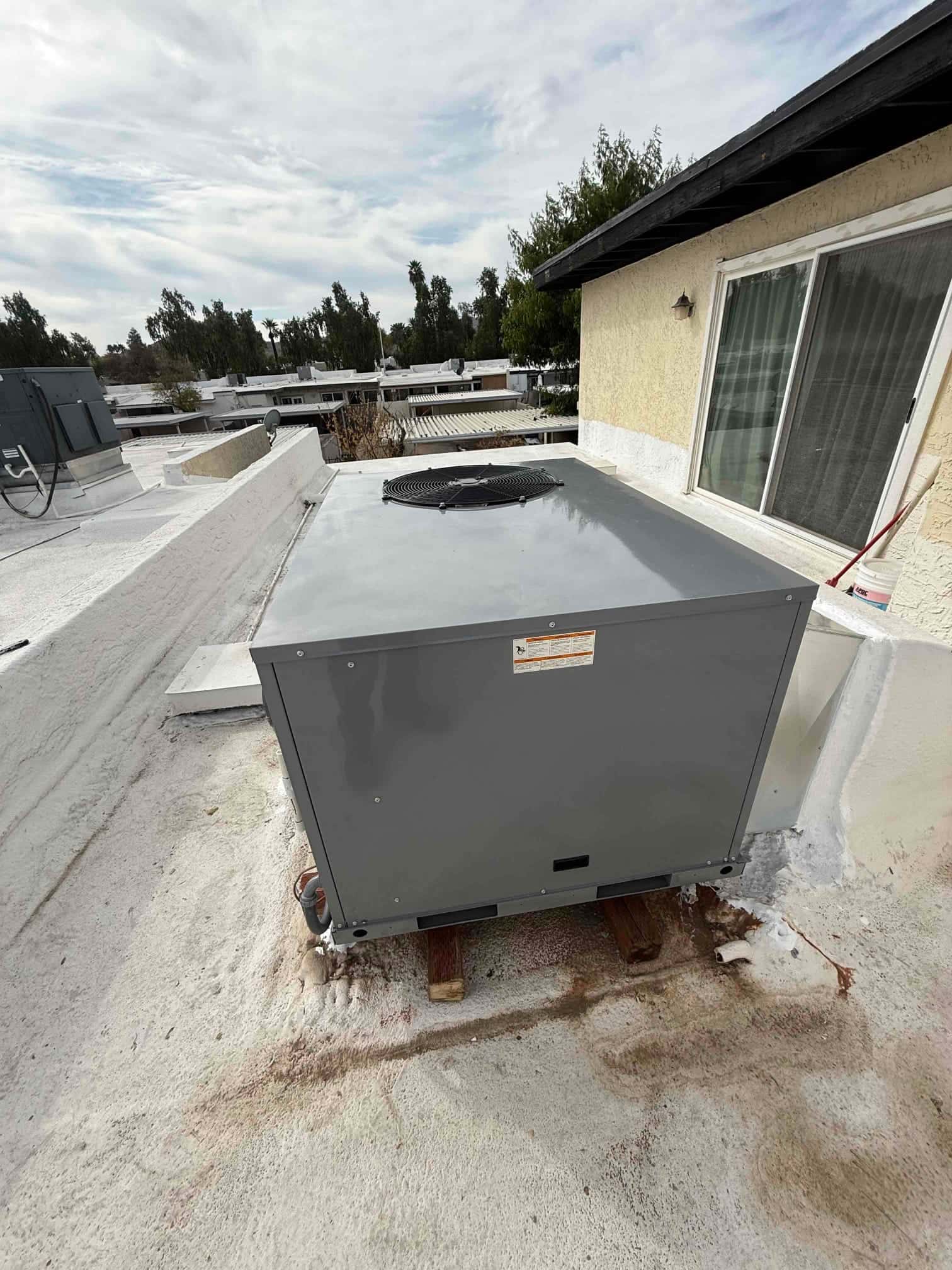 New rooftop package HVAC unit set on wood risers with disconnect and line set connections positioned at the rear.