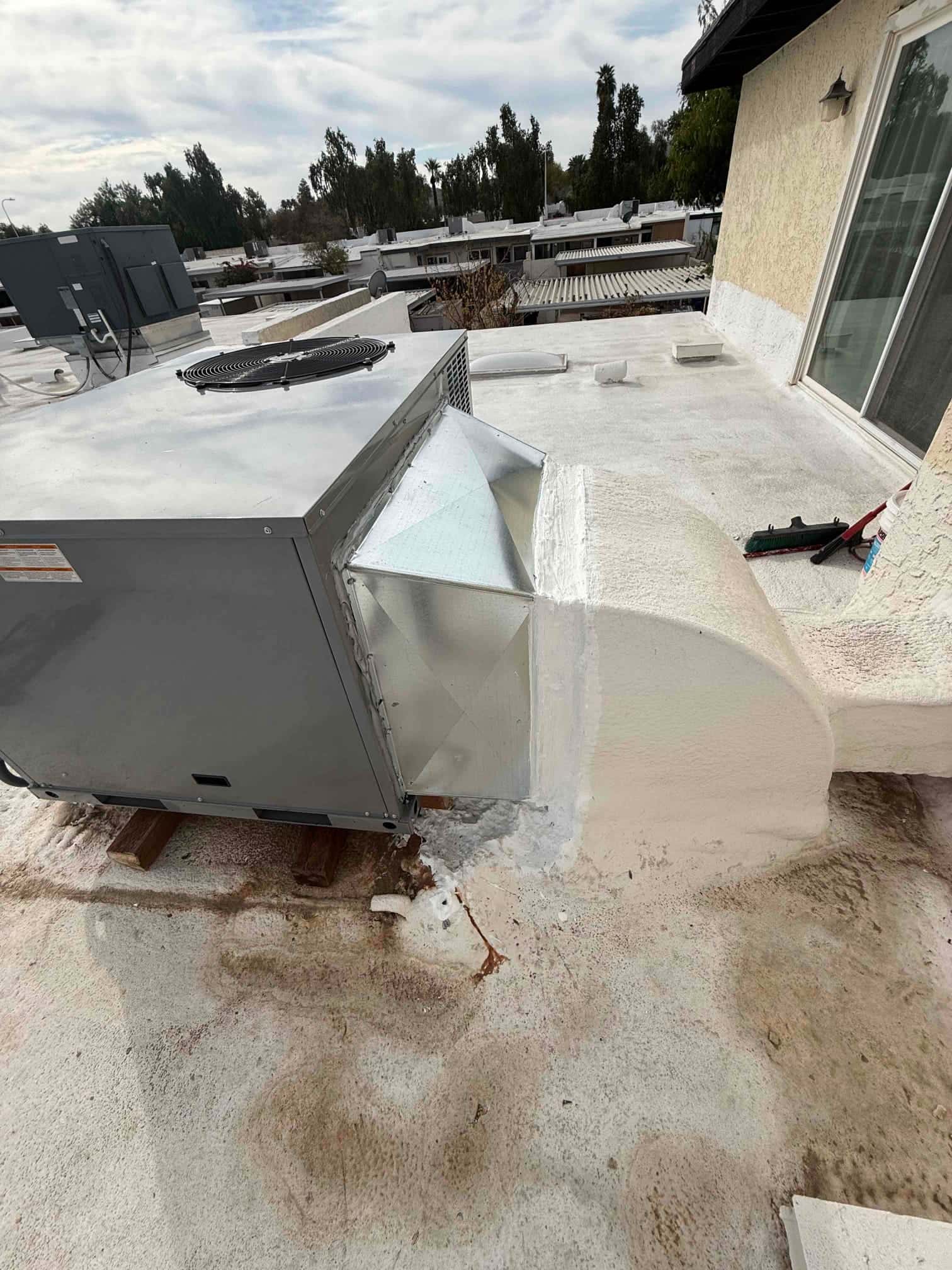 New rooftop package unit set on blocks with sealed supply and return duct transitions integrated into the roof curb.