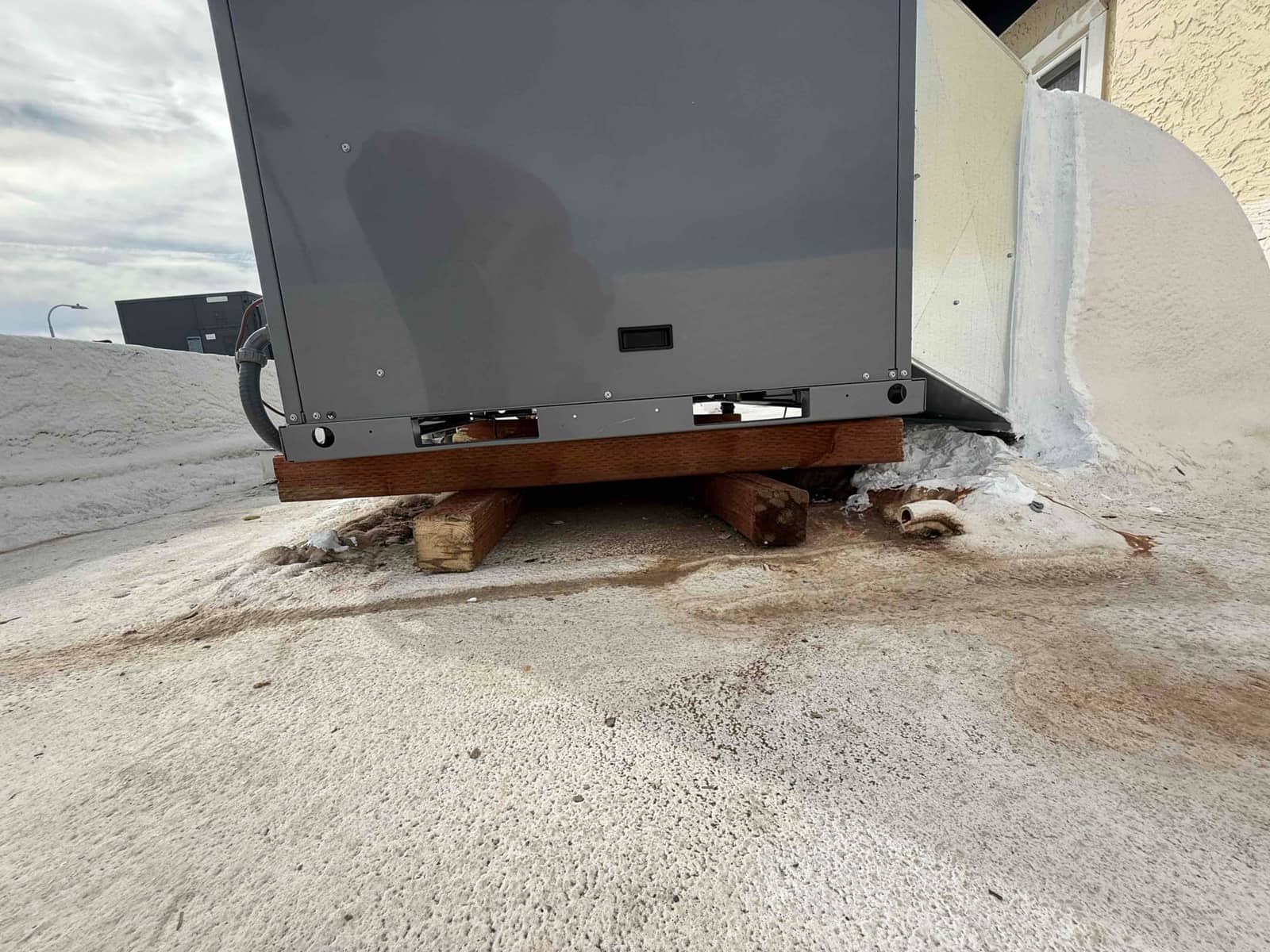 New rooftop package unit set on elevated wood sleepers with sealed duct connection and electrical conduit routed to the cabinet.