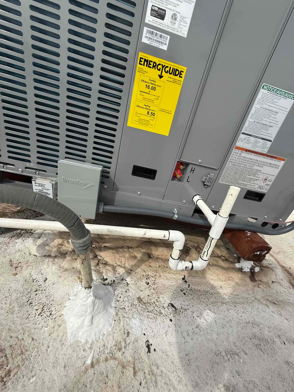 New rooftop package unit set with insulated refrigerant line, PVC condensate drain with cleanout, disconnect, and labeled service panel.