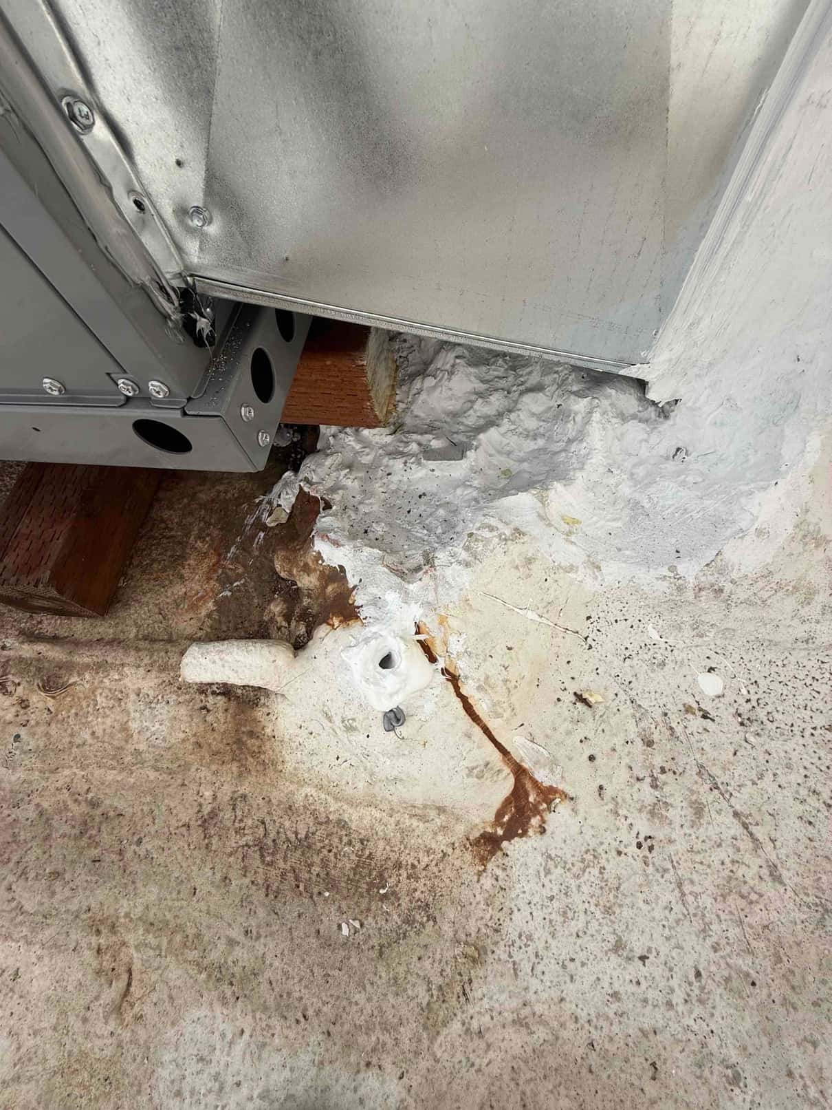 Package unit curb corner with sealed duct transition and roof penetration, showing drain stub-out and applied roofing sealant.