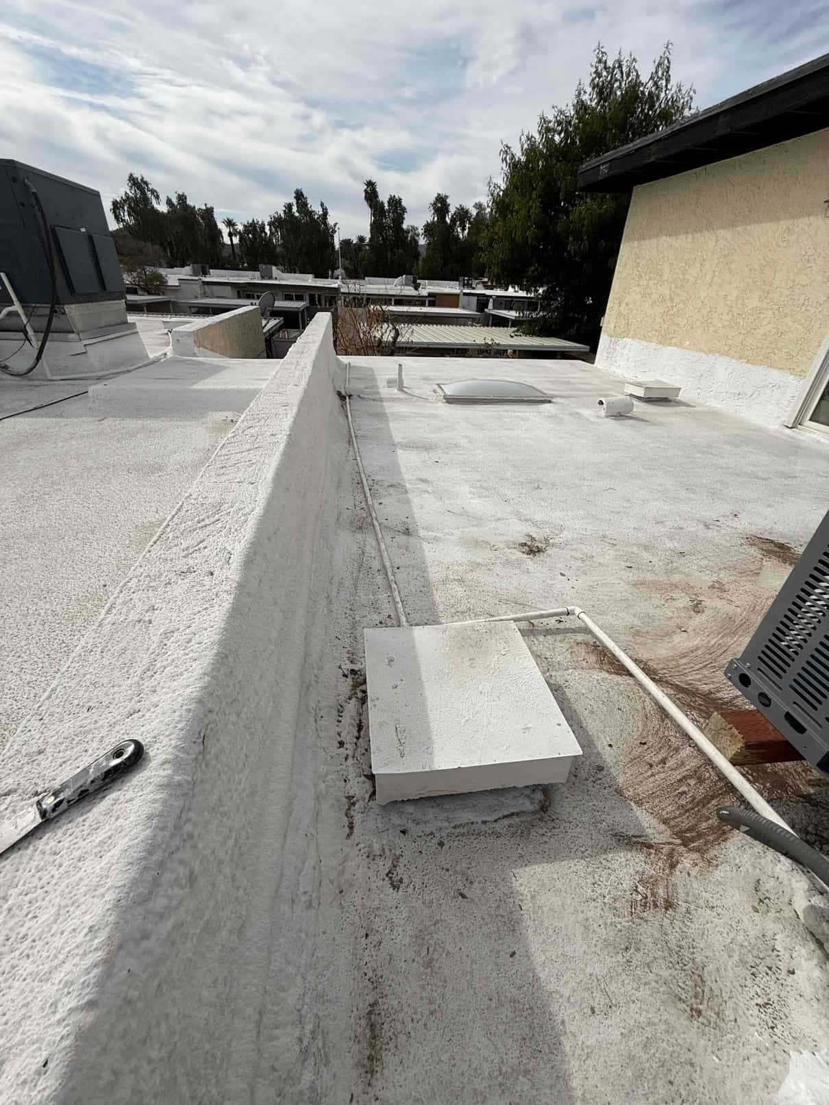 Rooftop installation area showing new package unit with routed condensate drain and rooftop curb, photographed after placement and sealing.