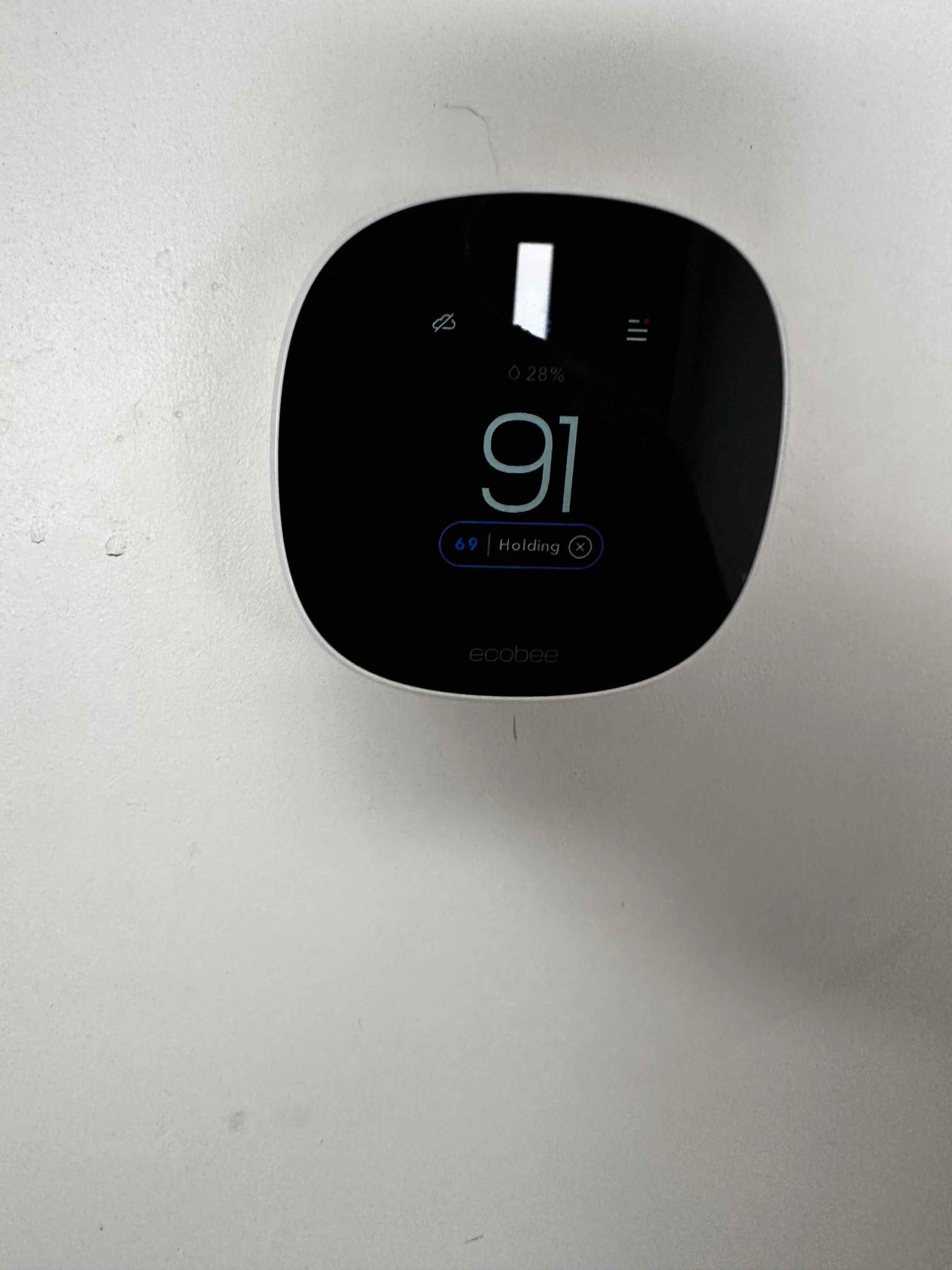 Wall-mounted smart thermostat displaying indoor temperature of 91 with a cooling setpoint held at 69.