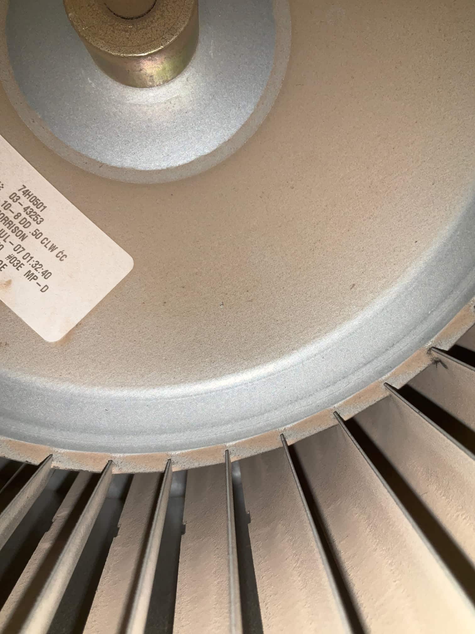 Blower wheel inside HVAC unit showing dust accumulation on the fins and hub.