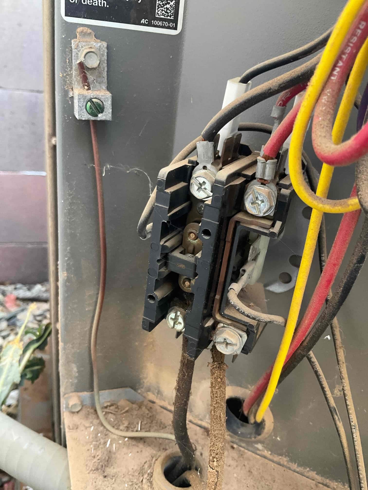 Contactor inside outdoor condenser cabinet, with connected black, red, and yellow wires and notable dust buildup.