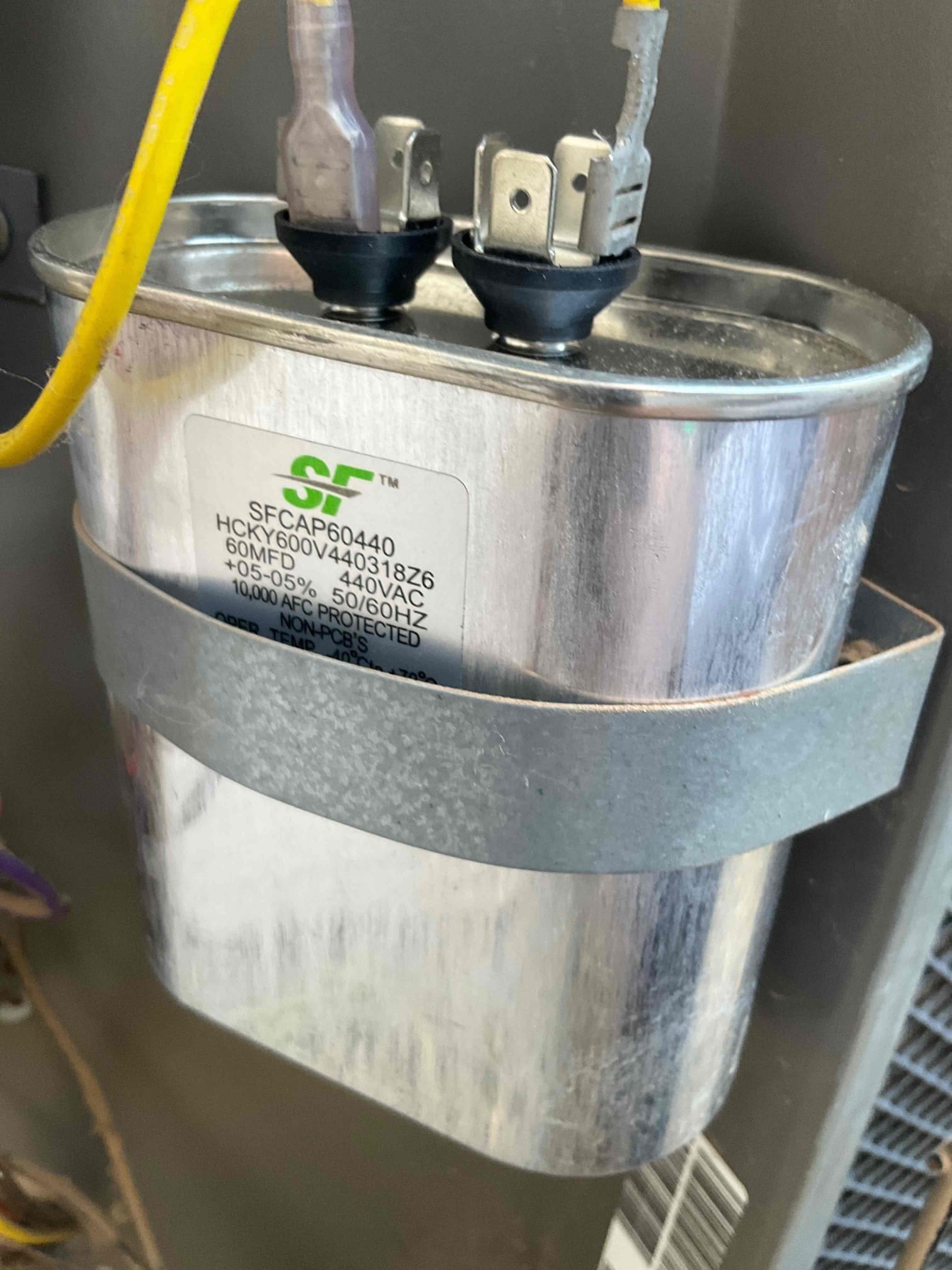 Oval capacitor mounted in the unit compartment; label reads 60MF ±5% 440VAC, wiring connected to its terminals.