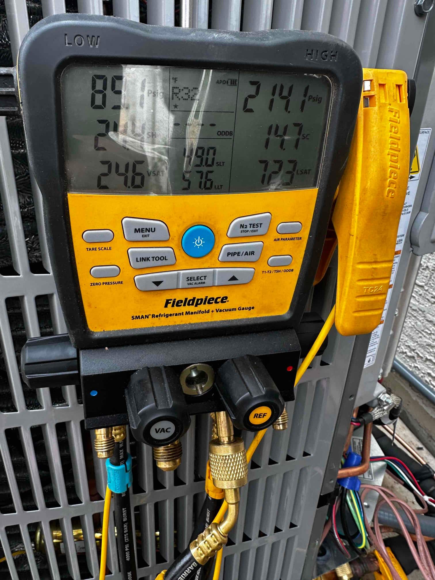 Digital manifold connected to the outdoor unit shows operating pressures with subcooling and saturation temperatures during system commissioning.