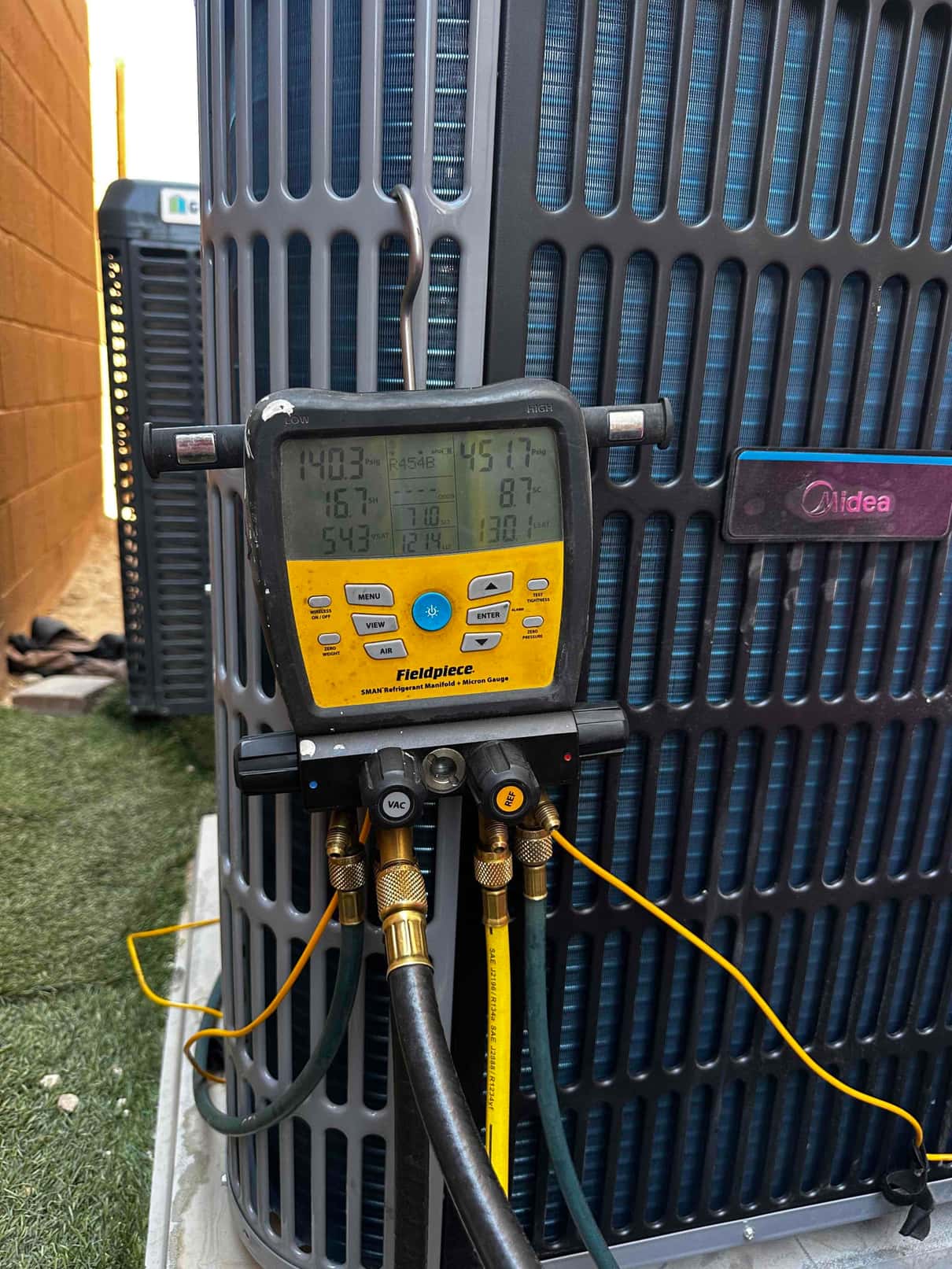 Digital manifold connected to the outdoor unit shows operating pressures and temperatures during system commissioning.