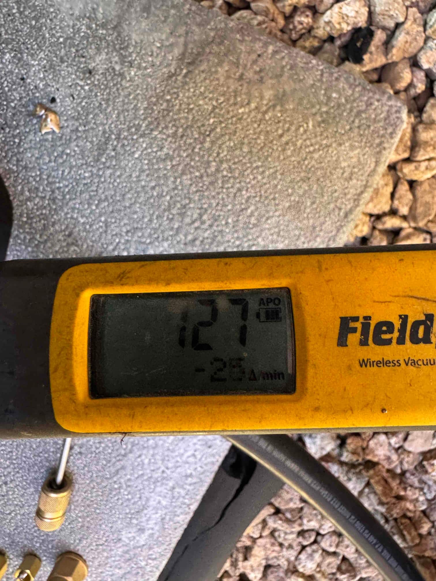 Digital micron gauge displays 127 microns during system evacuation, confirming a deep vacuum prior to refrigerant charging.