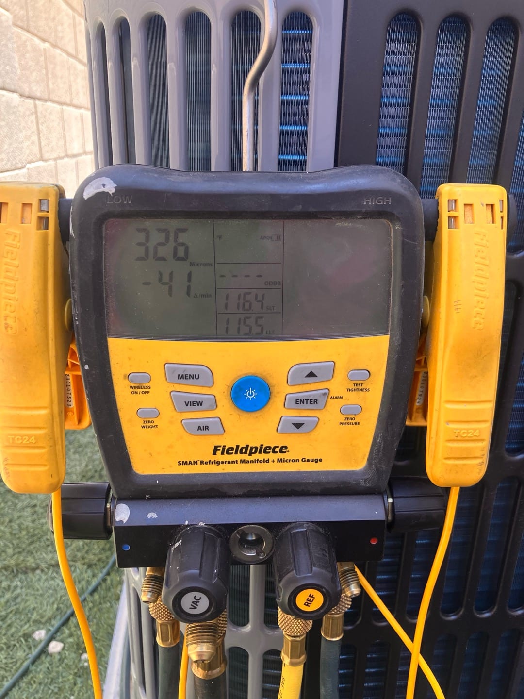 Digital micron gauge on the outdoor condenser shows 326 microns during evacuation before releasing refrigerant charge.