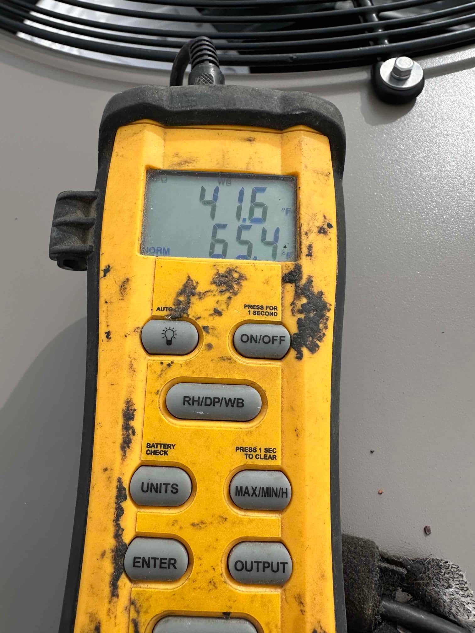 Digital thermometer shows 41.6°F and 65.4 on the display while measuring air temperature at the outdoor unit.