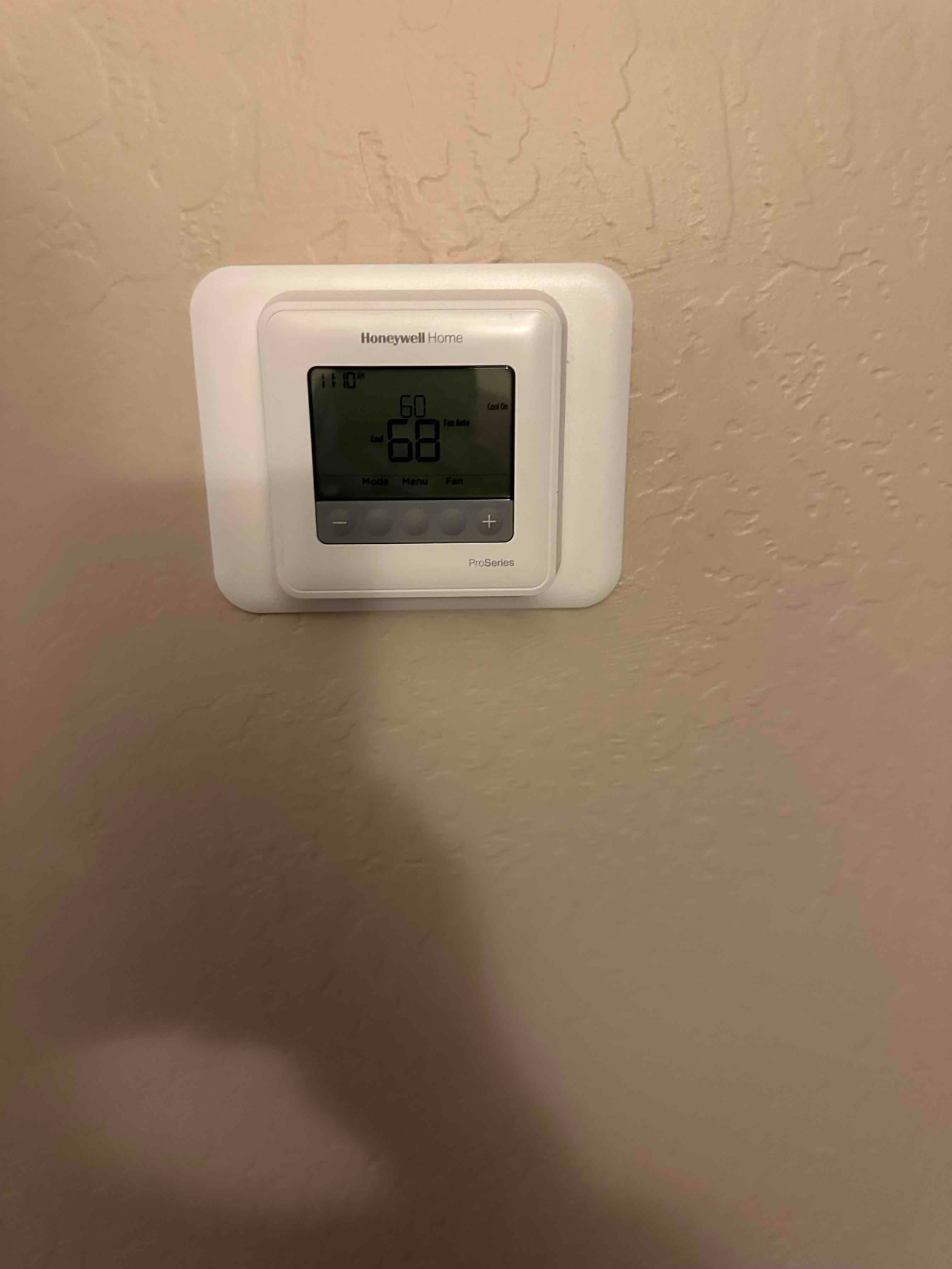 Wall-mounted digital thermostat installed and set to cool mode with a target temperature displayed.