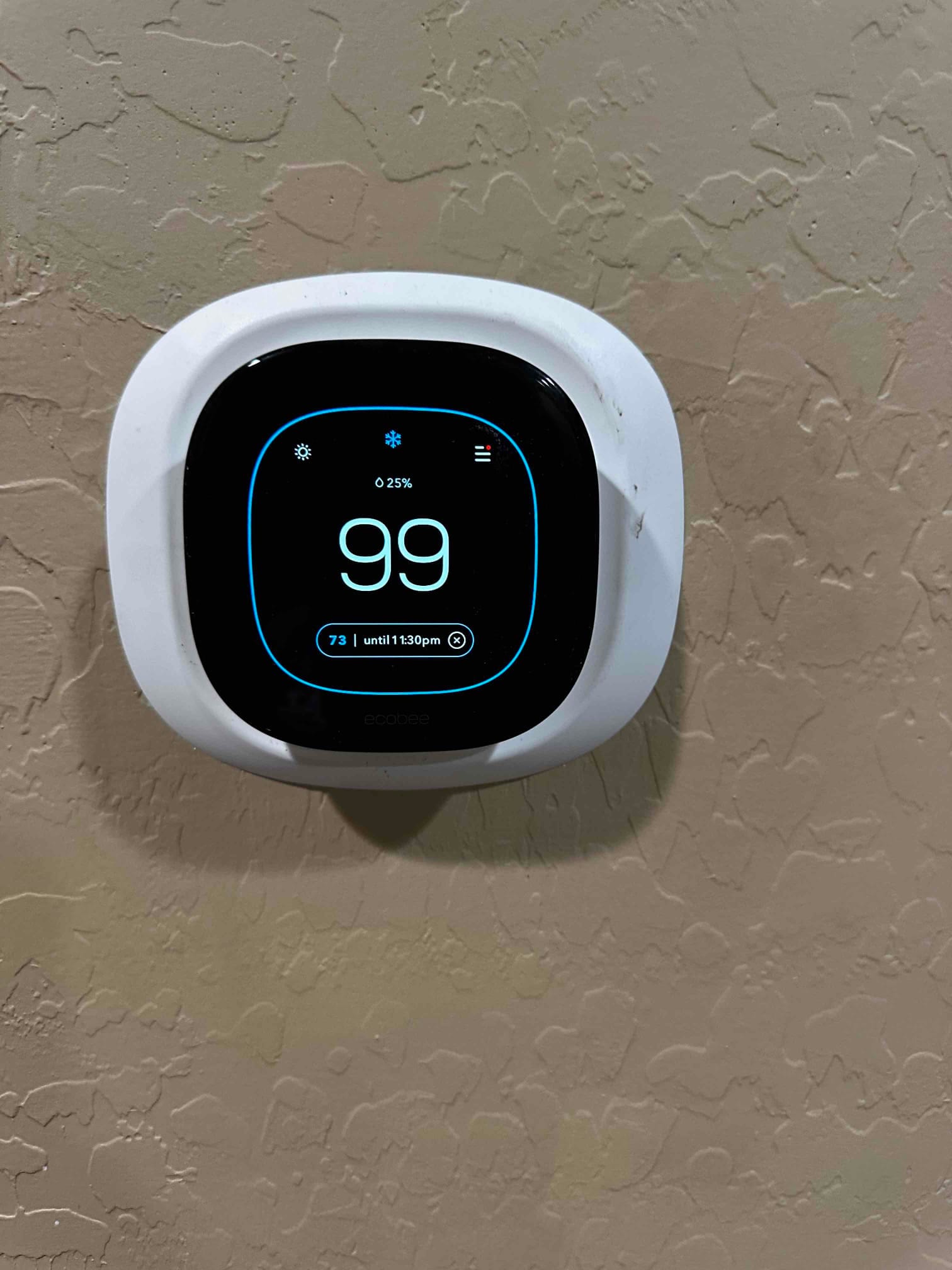 Wall-mounted smart thermostat displays cooling mode with setpoint shown, confirming control installation and interface operation.