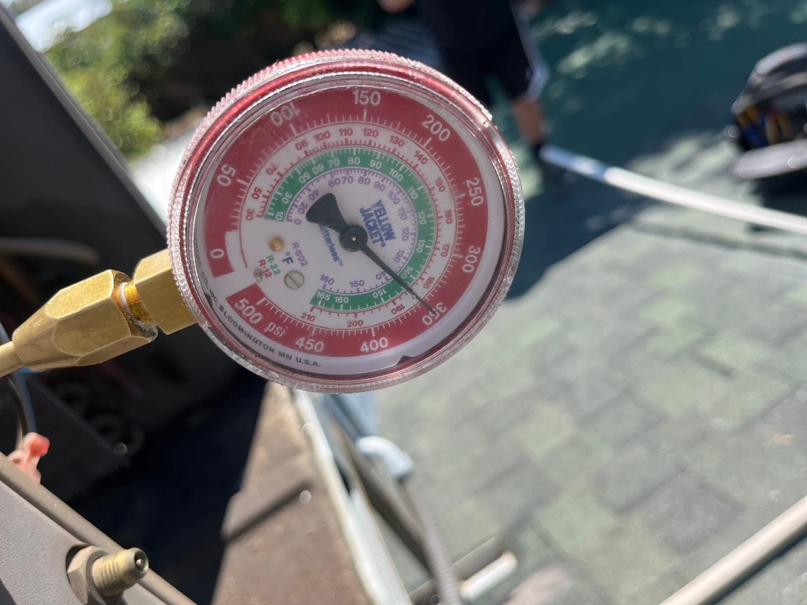 Analog refrigerant manifold gauge connected at the service port during air conditioning diagnostic testing.
