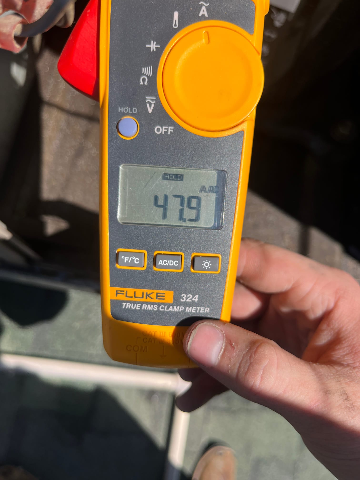Clamp meter display shows 47.9 A in AC current mode while measuring an electrical conductor on the HVAC system.