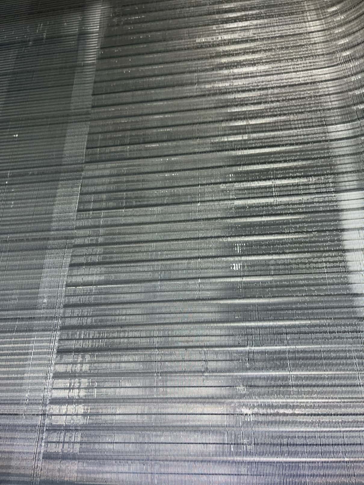 Close-up of an evaporator coil surface showing clean aluminum fins after detailed cleaning during maintenance.