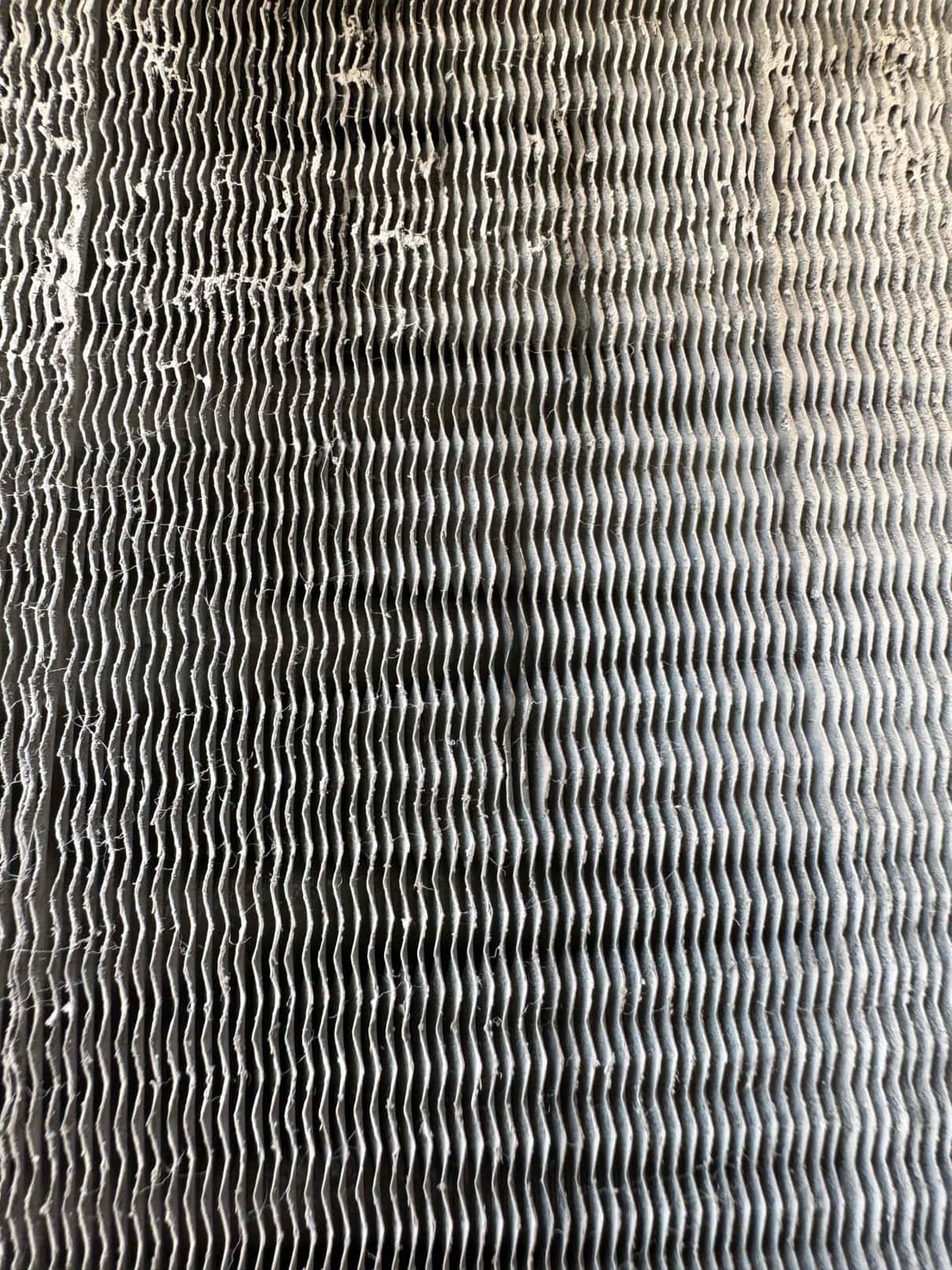 Close-up of an HVAC coil surface with accumulated dust and debris packed between the fins.
