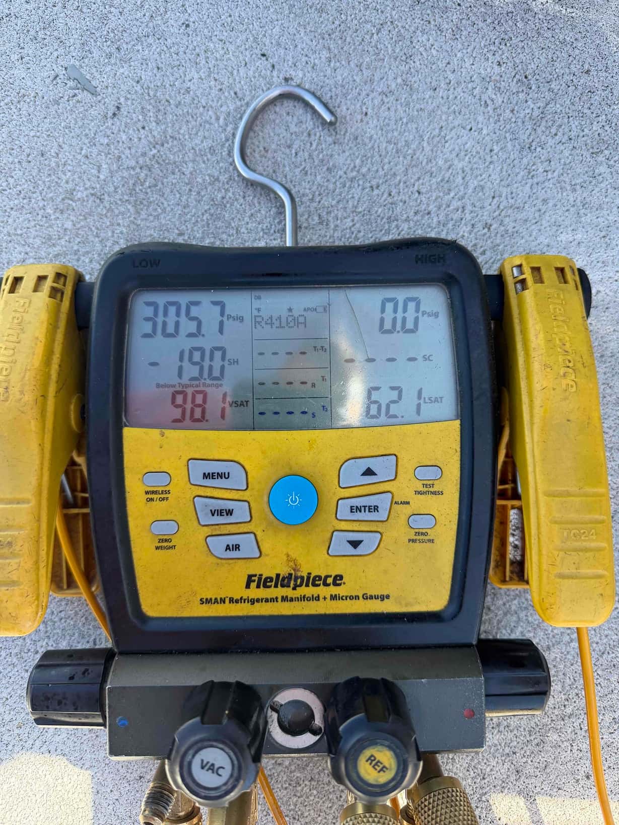 Digital manifold gauge set displays 305.7 PSIG on the low side and 0.0 PSIG on the high side with clamps attached.
