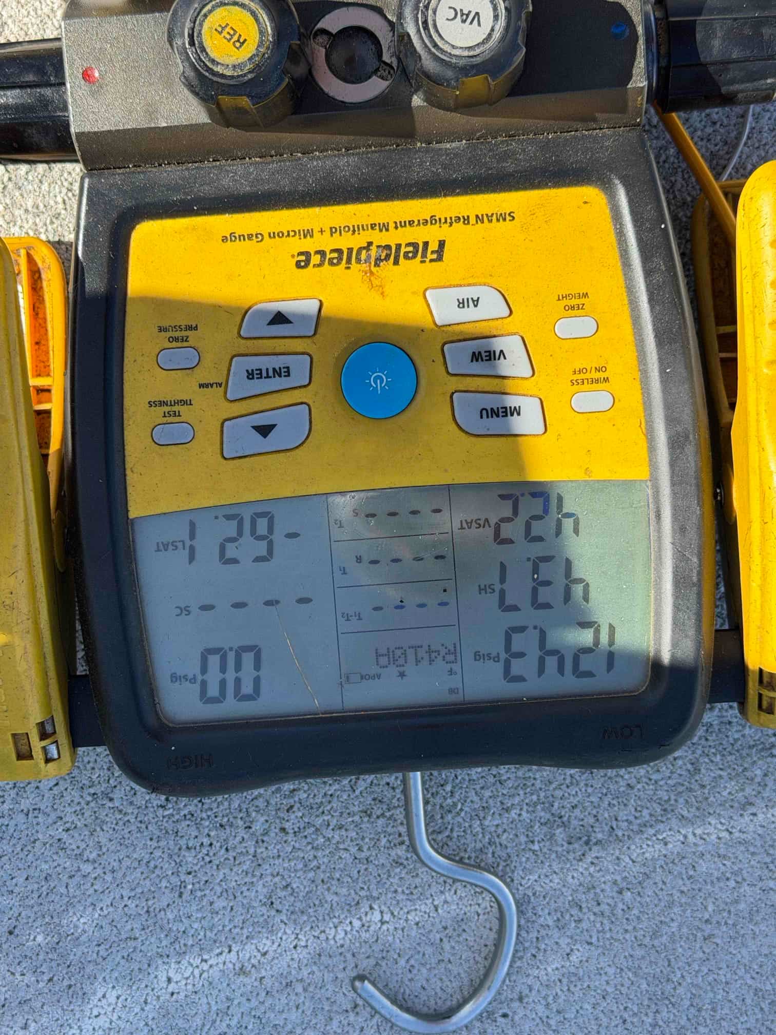 Digital micron gauge on a manifold shows a deep vacuum achieved during system evacuation prior to refrigerant charging.