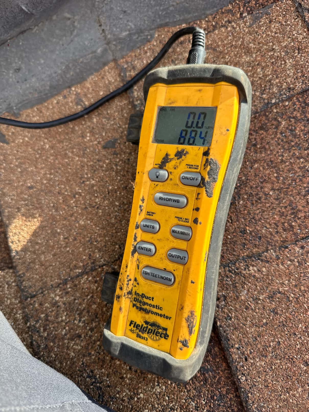 Digital thermometer with probe connected displays 88.4 degrees Fahrenheit, documenting return air temperature during commissioning.