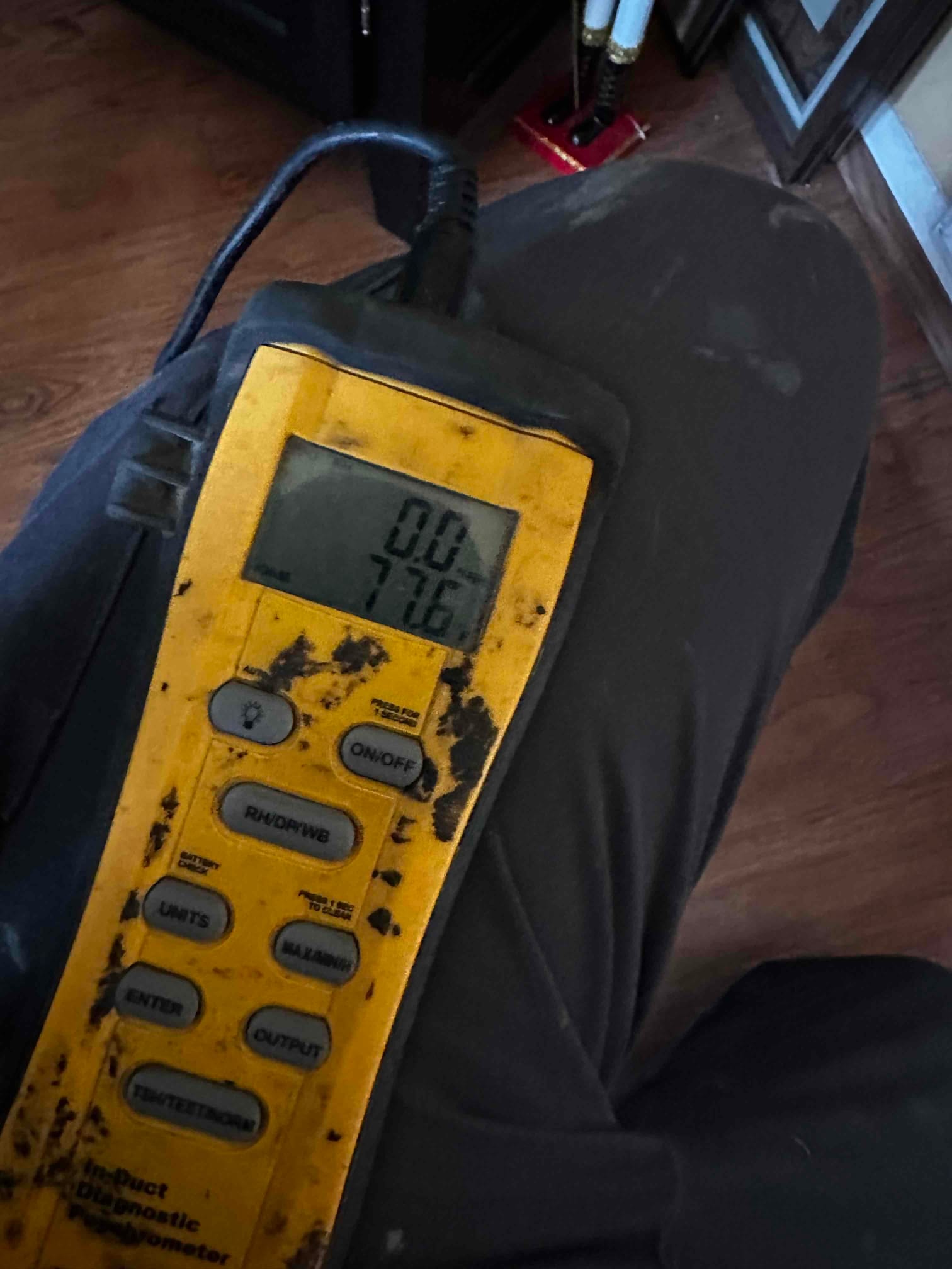 Digital thermometer shows 77.6 degrees Fahrenheit, documenting indoor return air temperature during commissioning.
