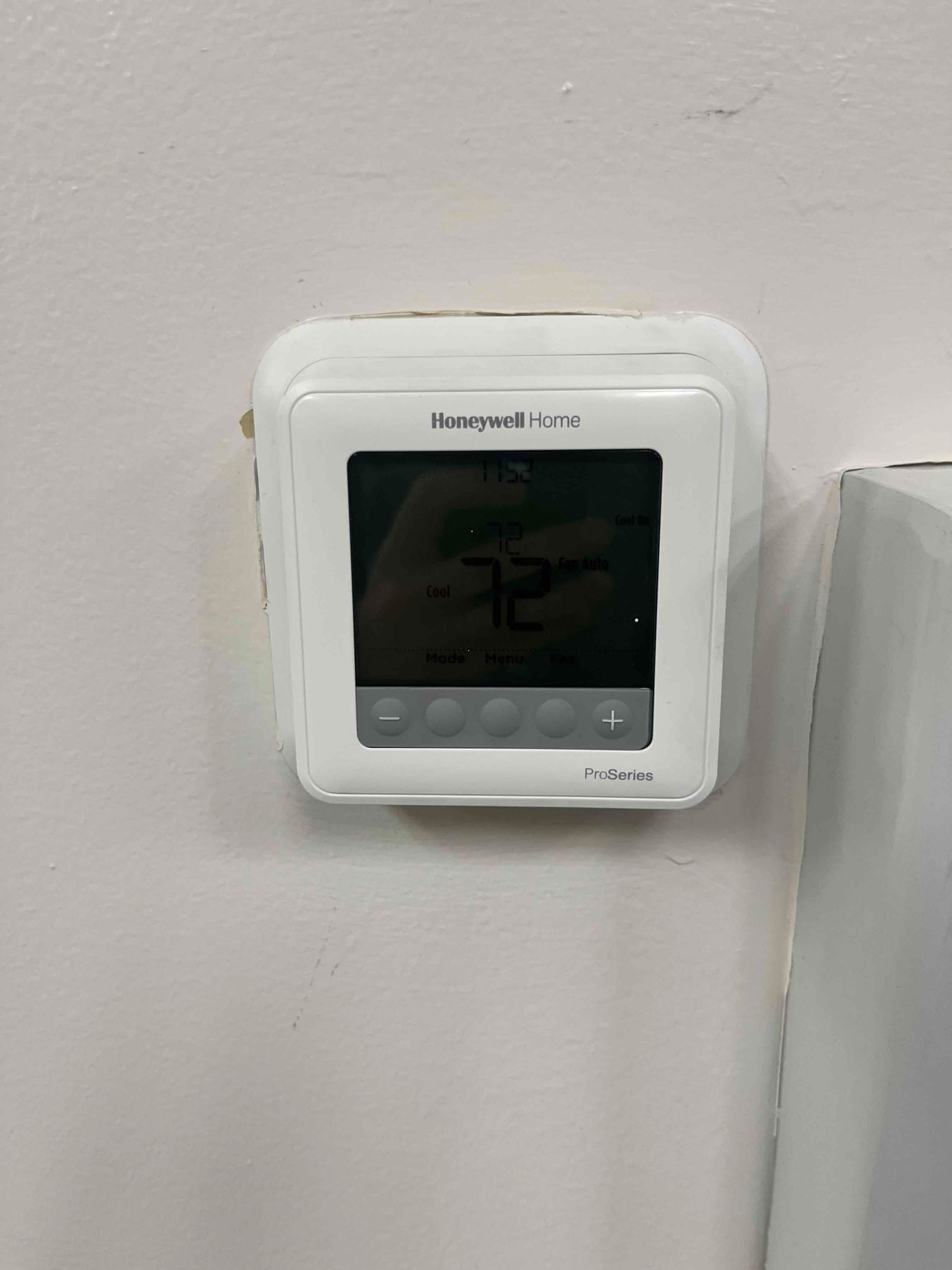 Digital thermostat on wall displays 72°F room temperature with cooling mode indicated and system status icons visible.