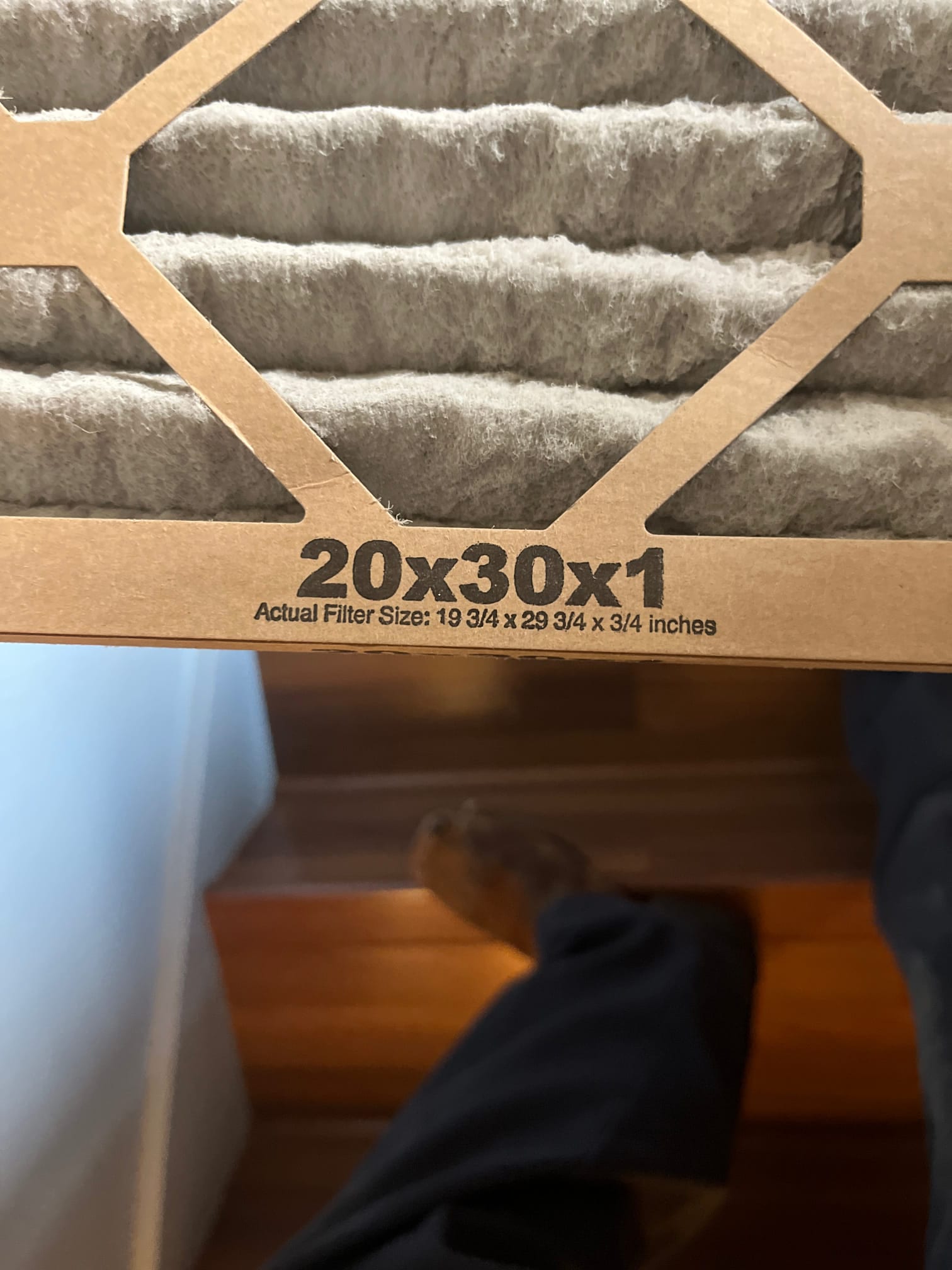 Dirty 20x30x1 air filter removed for replacement, showing accumulated dust on pleats and printed size specifications.