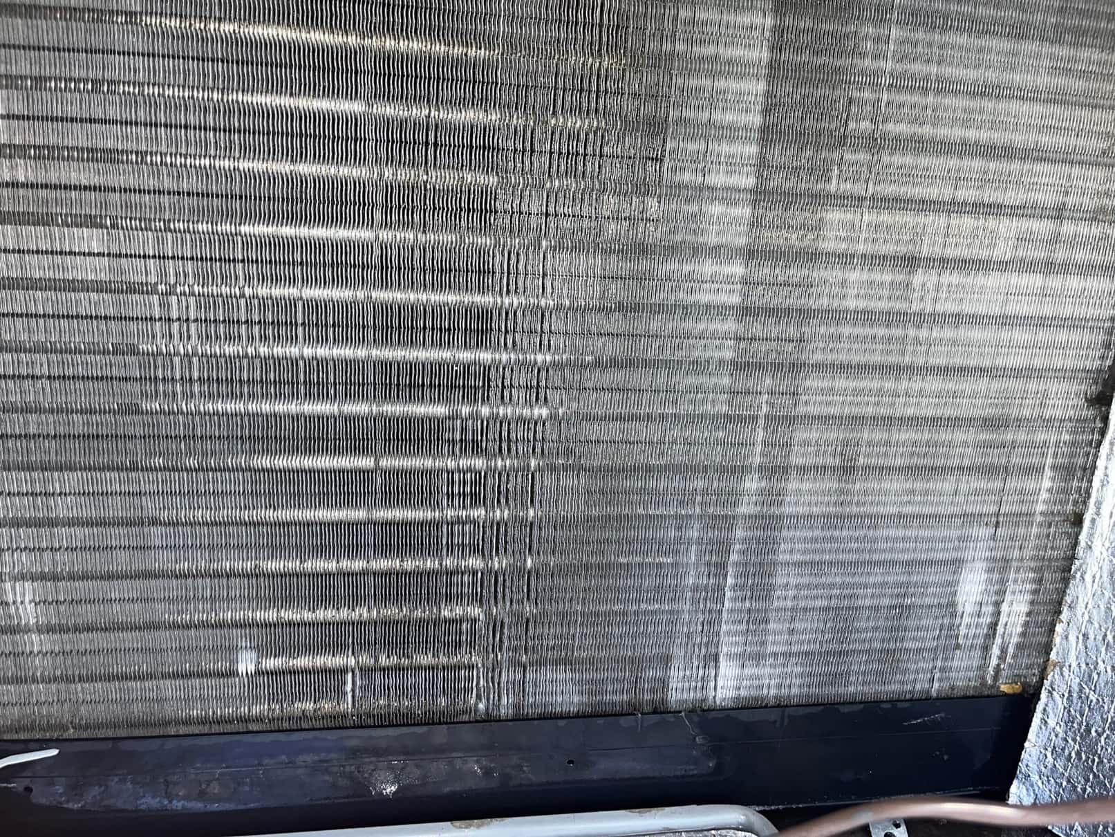 Dirty evaporator coil fins with visible dust and debris accumulation across the surface before cleaning.